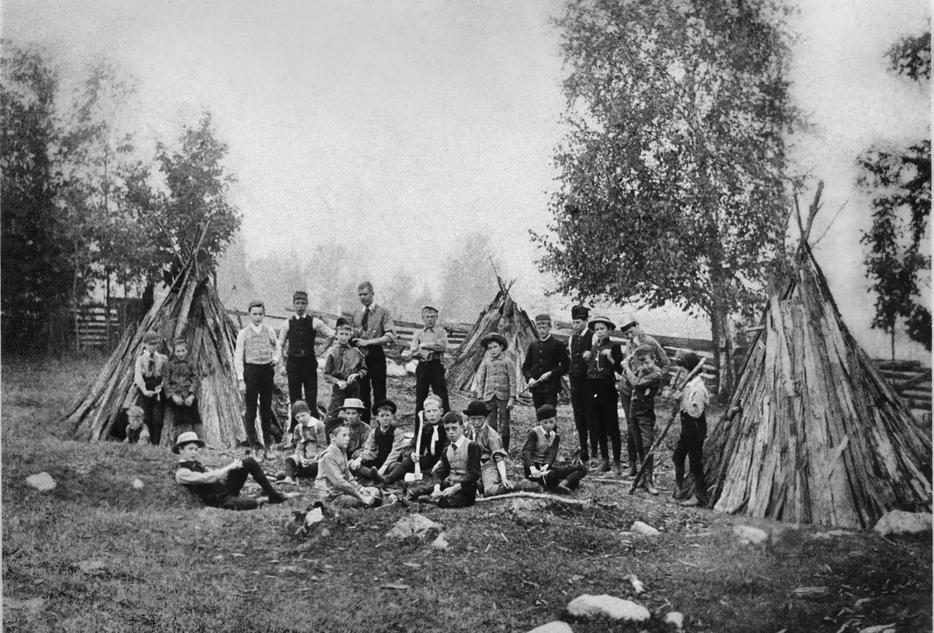 Archival photograph of students standing by teepees