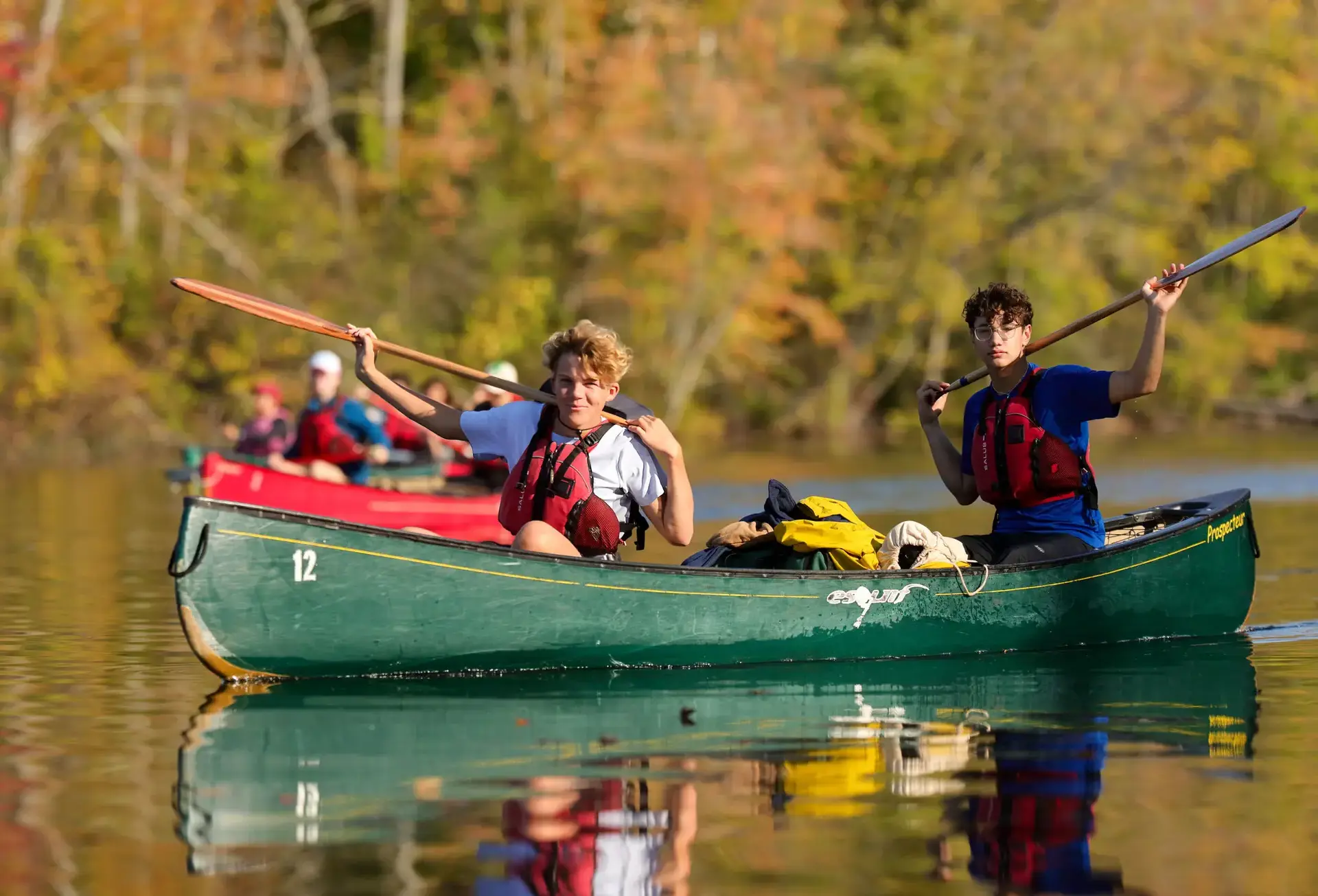 Students sitting in canoe, holding up their oars