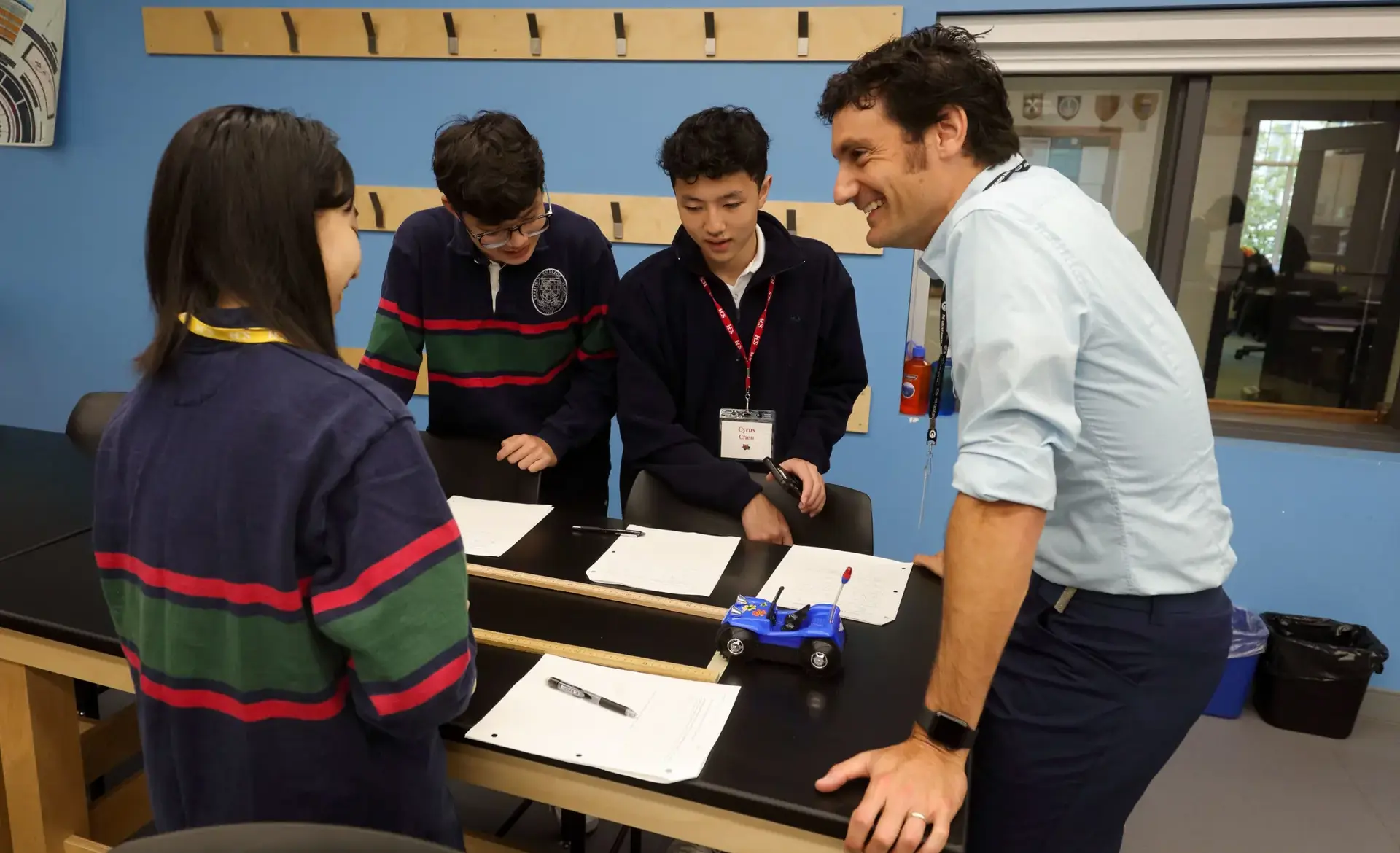Teacher chatting with students at desk