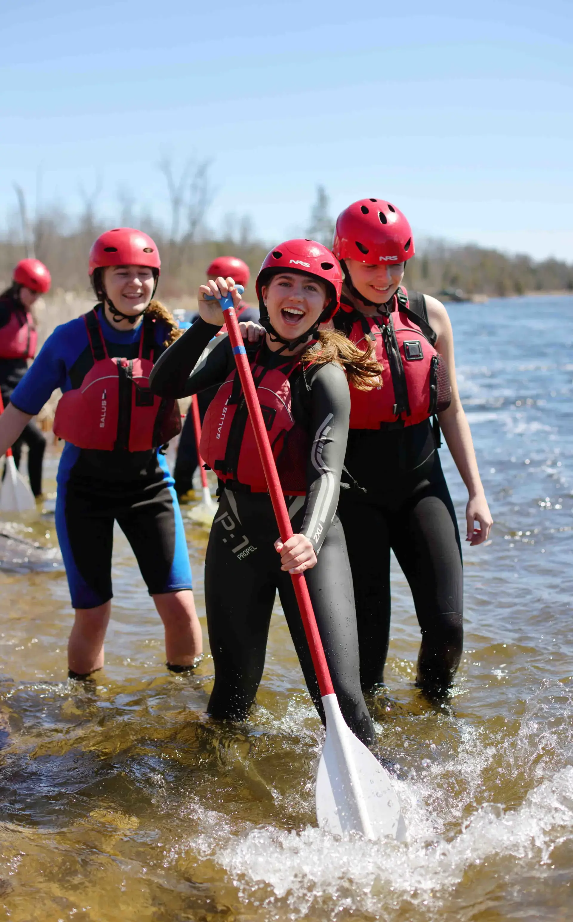 Students standing in river, holding oars