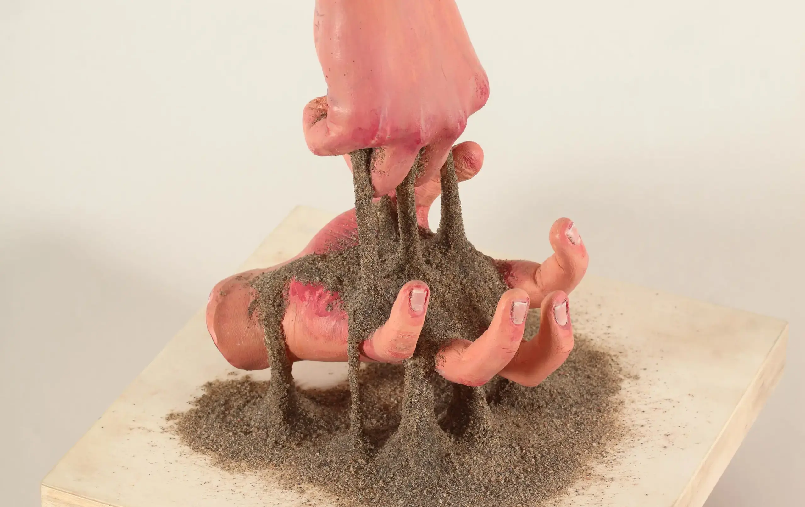 Sculpture of sand passing through two disembodied hands
