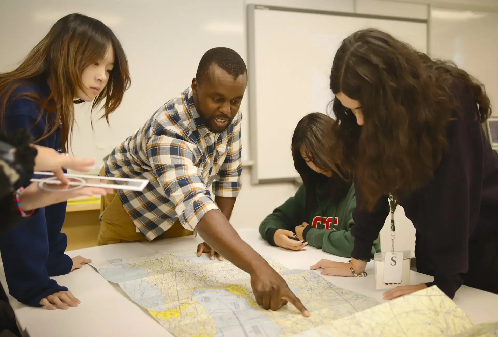 Teacher demonstrating to students who stand around desk