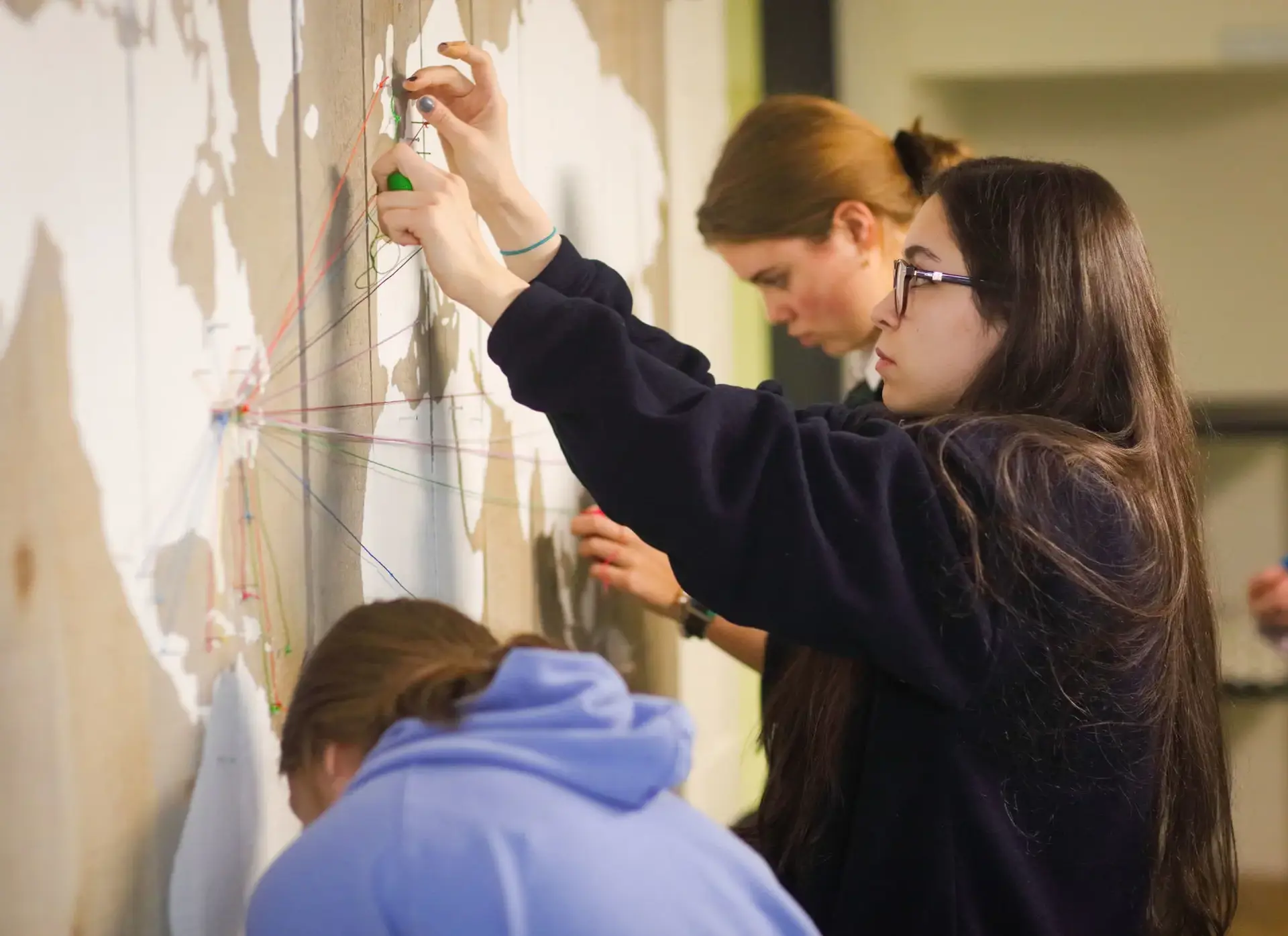 Students pinning threads to map