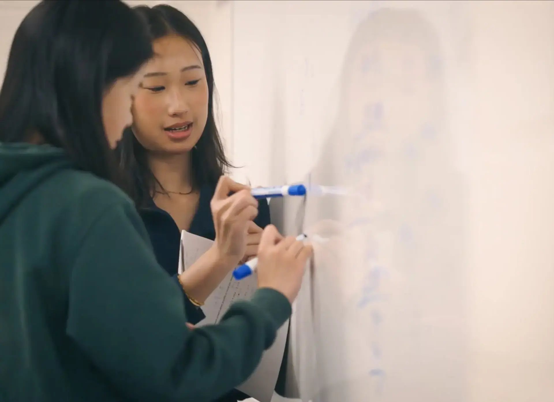 Two students writing on whiteboard