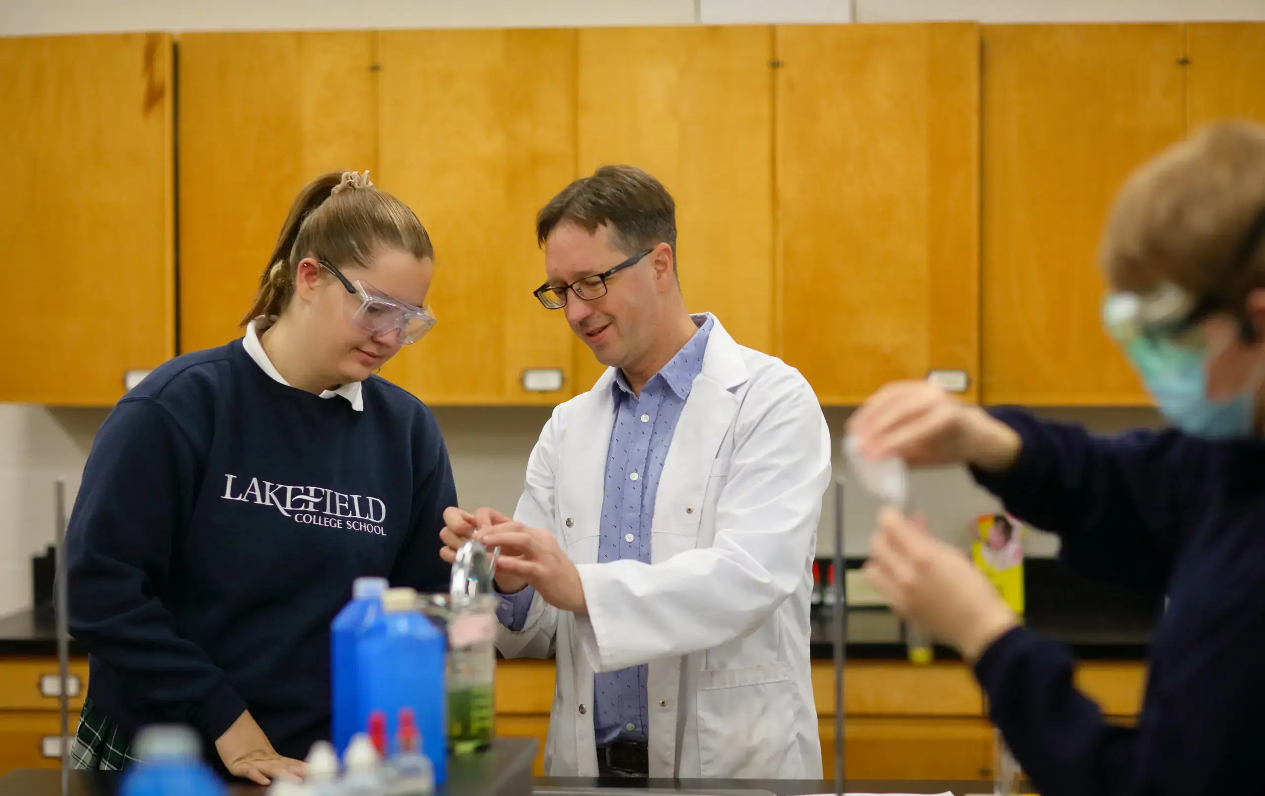 Teacher and student wearing lab gear, performing experiment