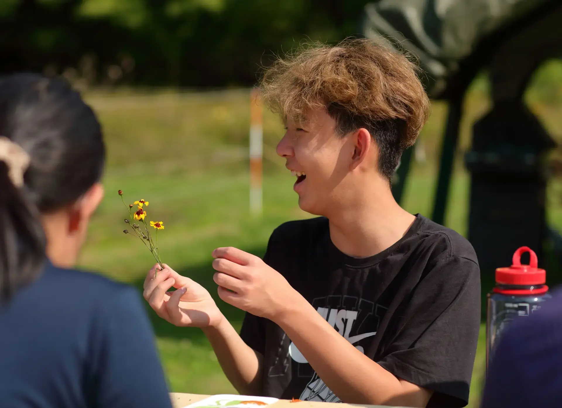 Smiling student holding up flower
