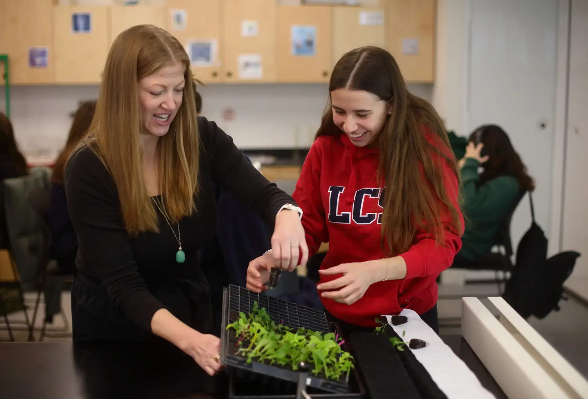 Two students working with plant, laughing