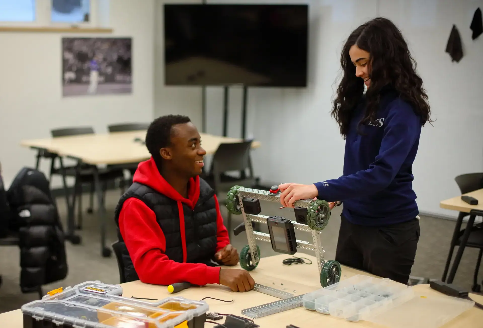 Two students smiling, working with engineering project