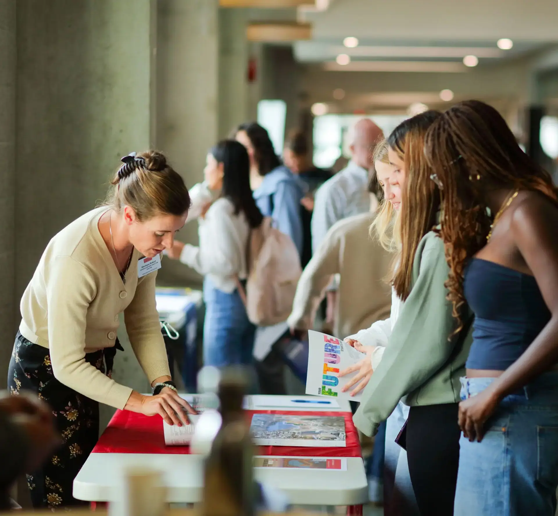 A university representative speaks with three students at a guidance fair. 