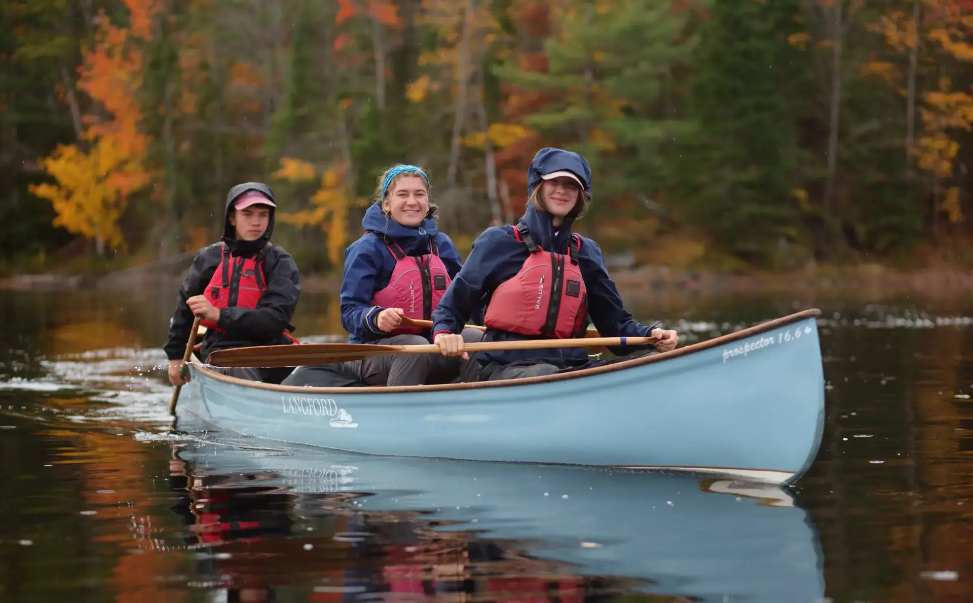 Three students sitting in canoe