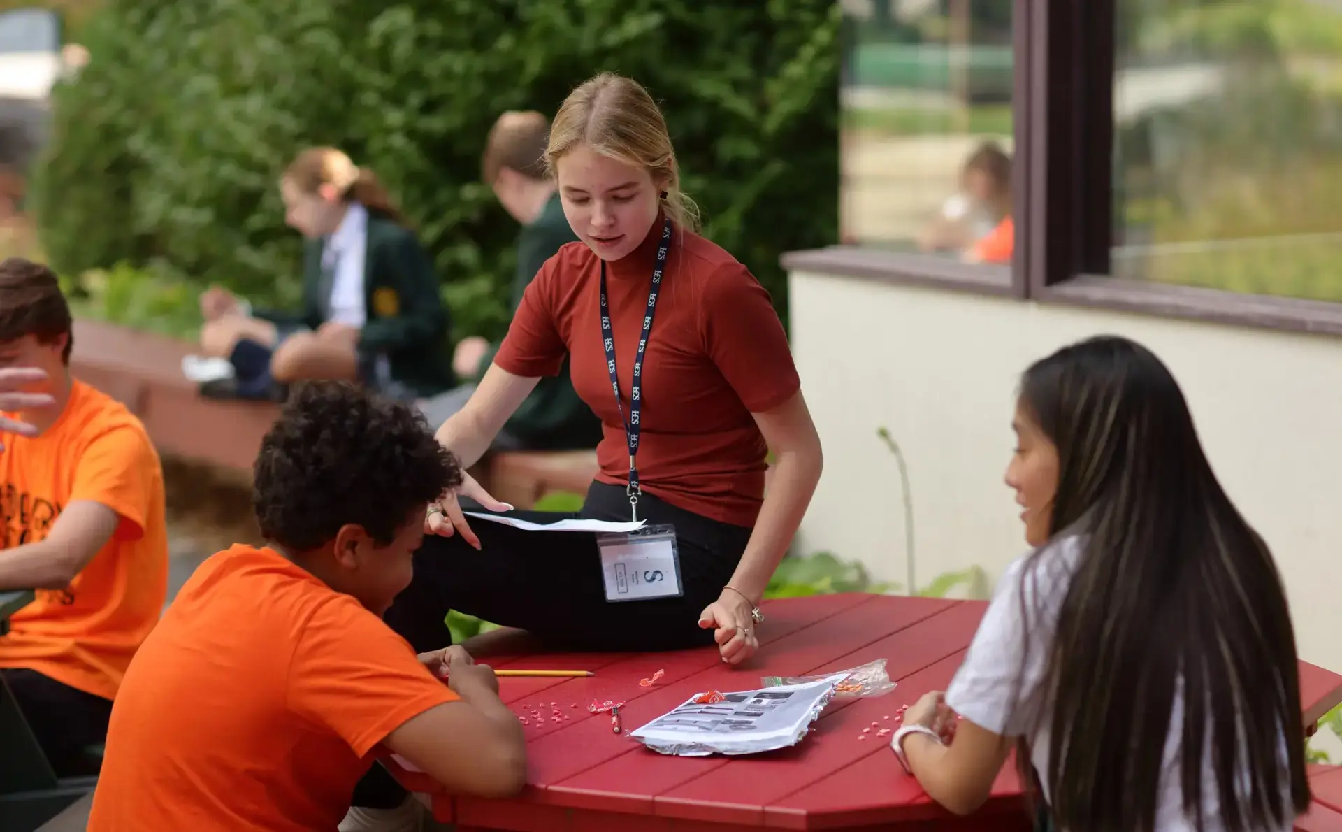 Teacher chatting to students as they work outside
