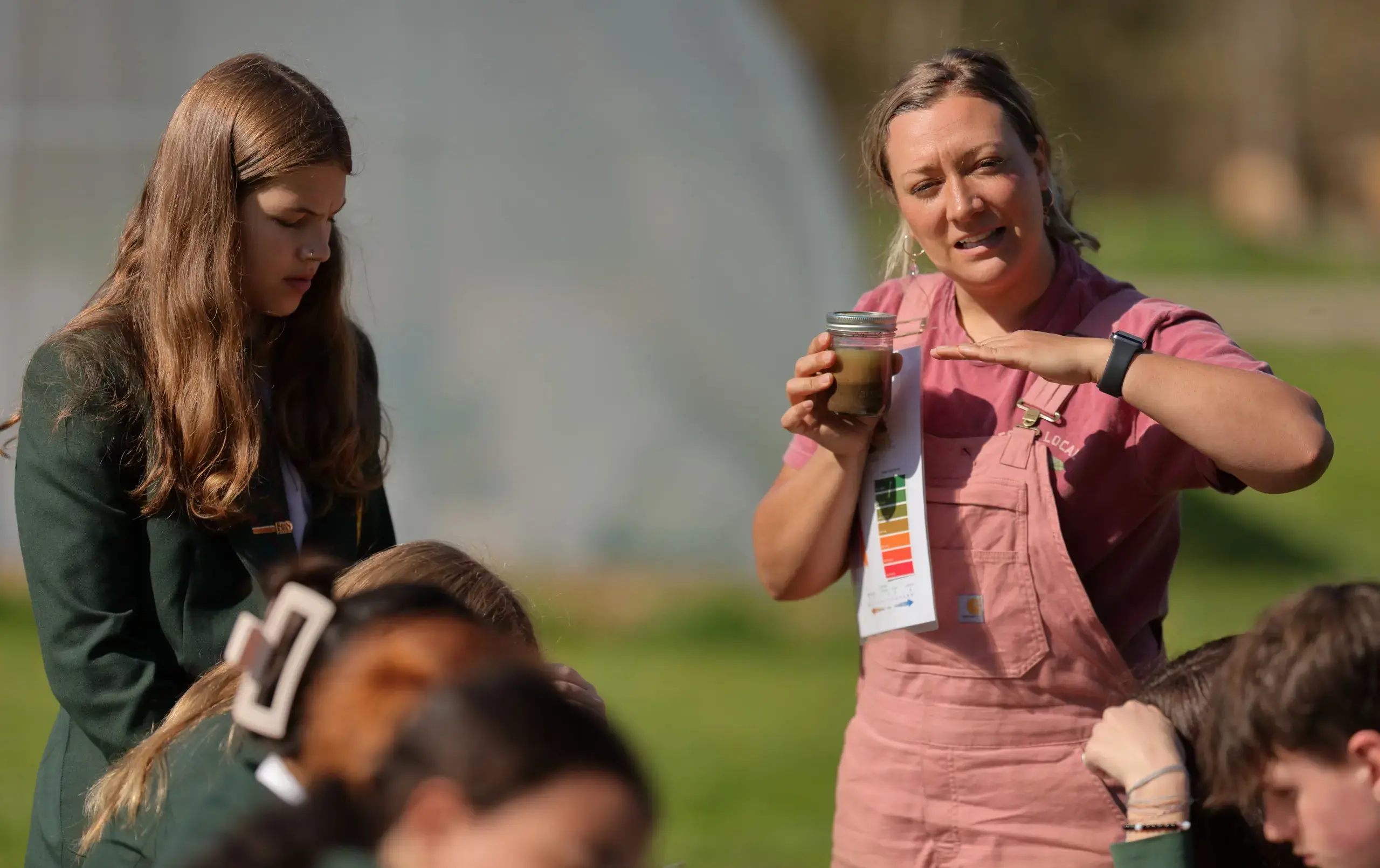 Teacher instructing students, holding soil sample