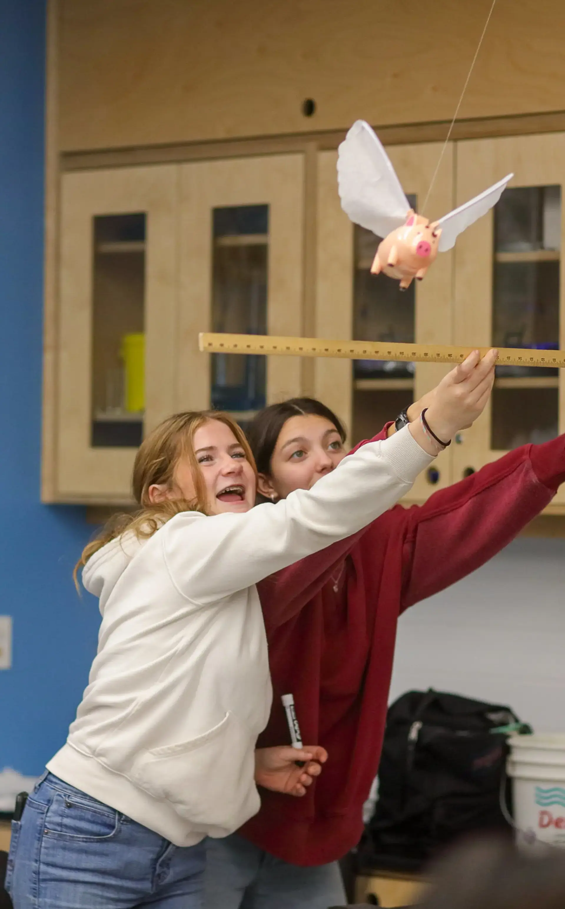 Two students holding up ruler during flying pigs experiment