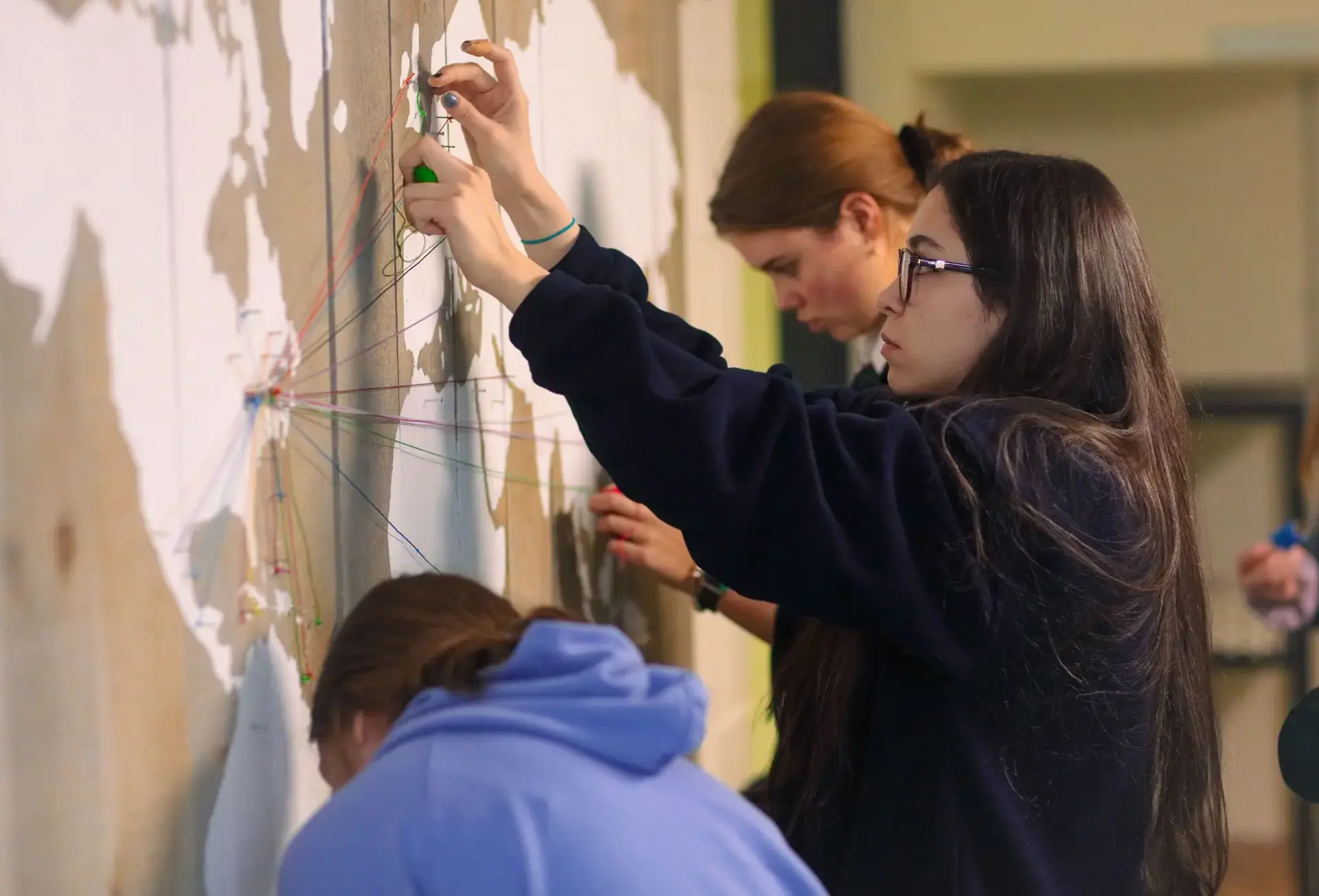Students pinning thread to map of world
