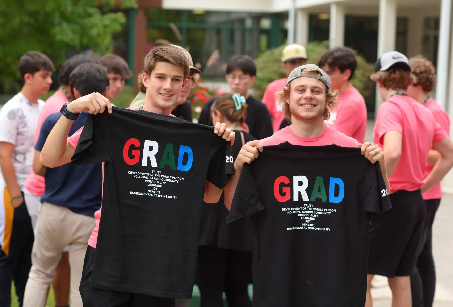 Two students holding 'grad' t-shirtd