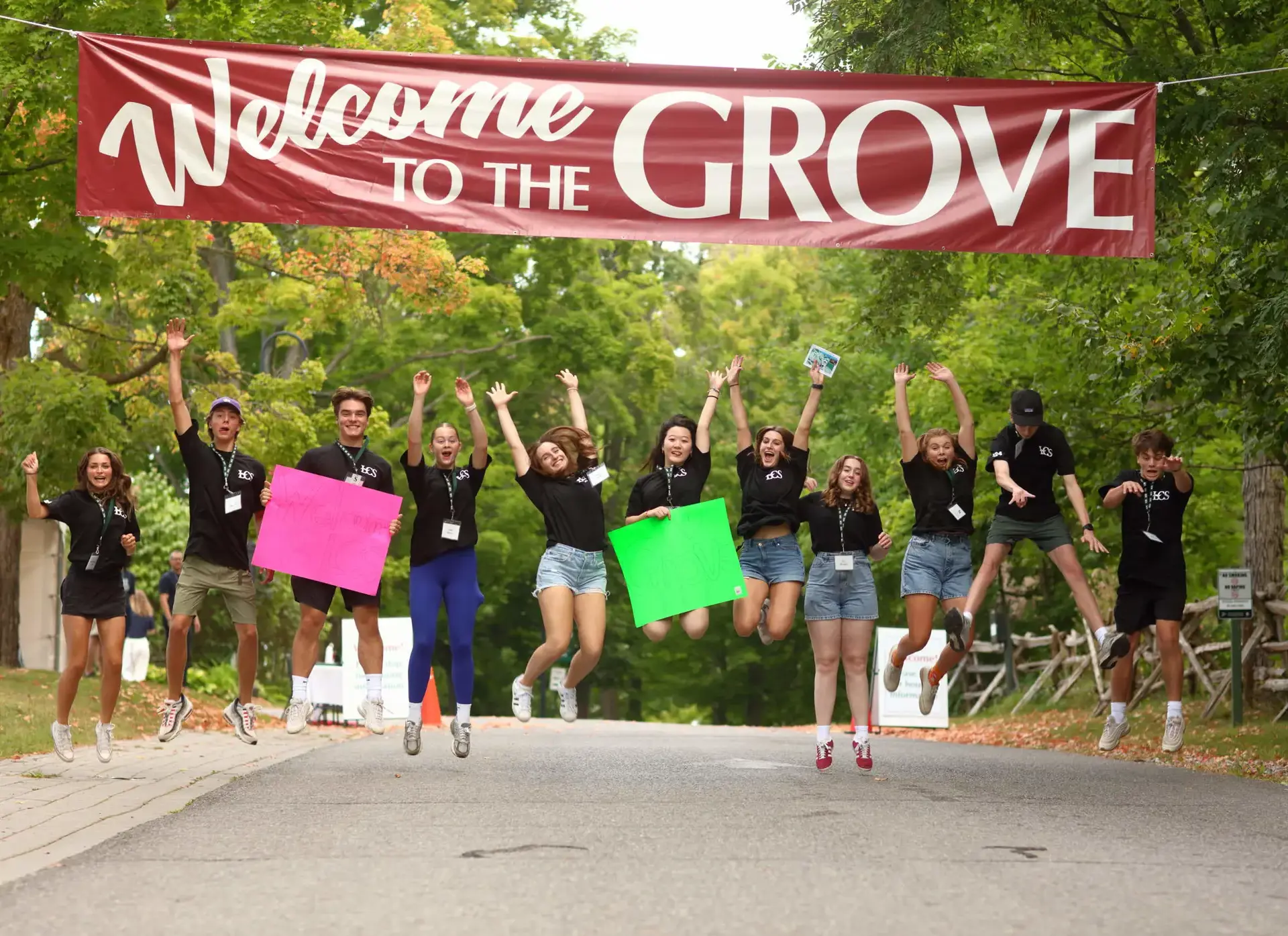 Students jumping in air, underneath Welcome to The Grove banner