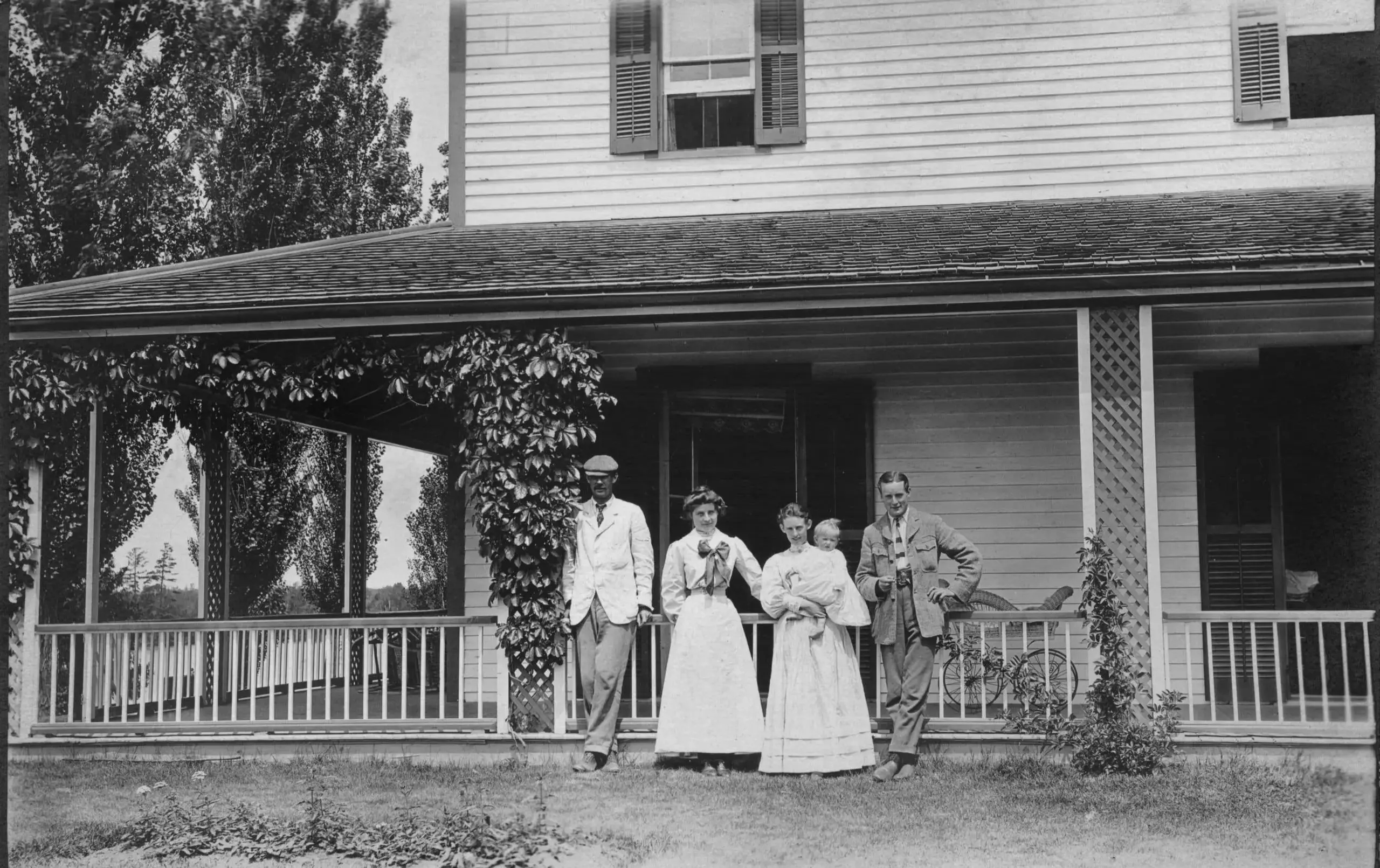 Old photograph of people standing in front of farmhouse