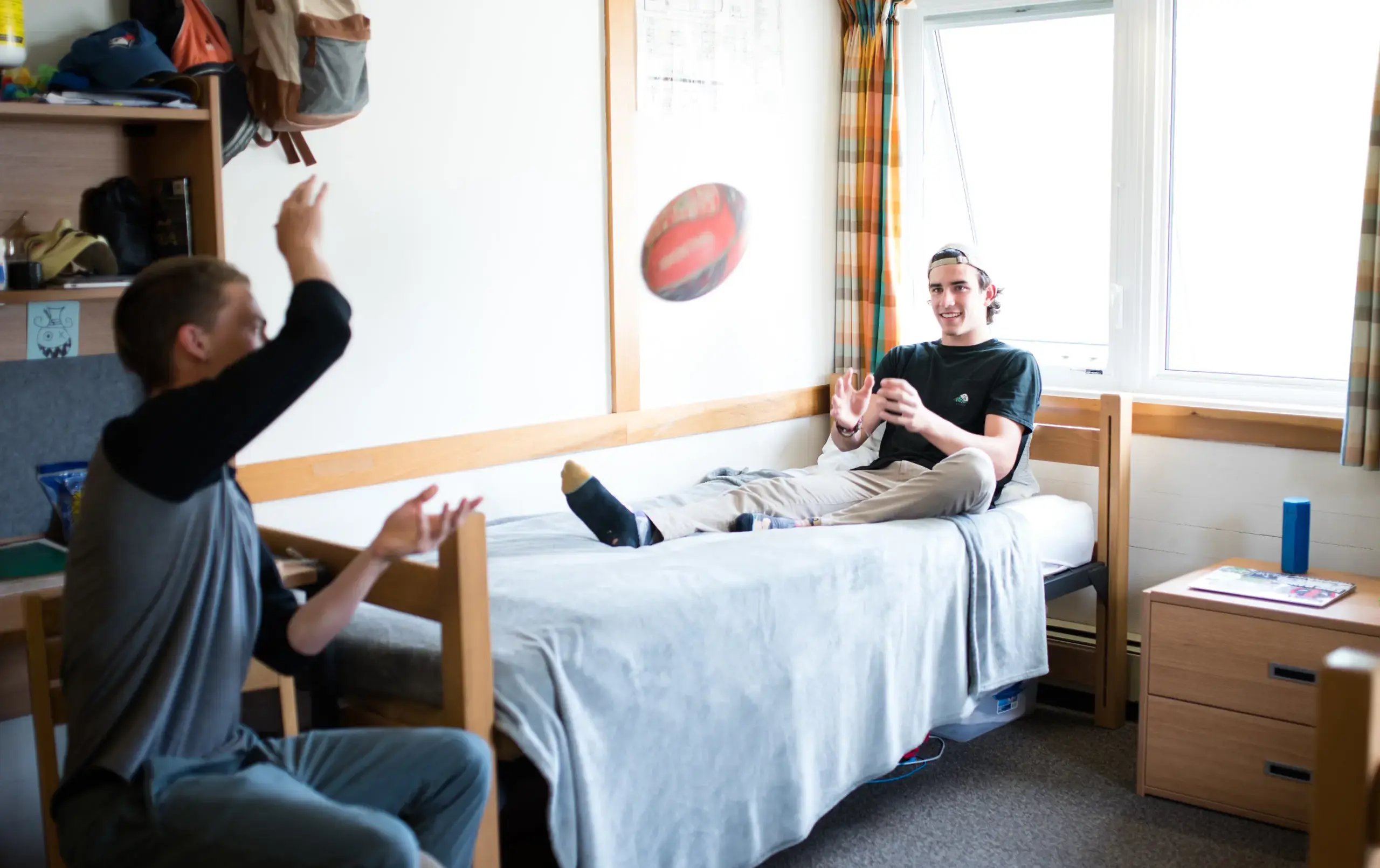 Students tossing football between each other in dorm room