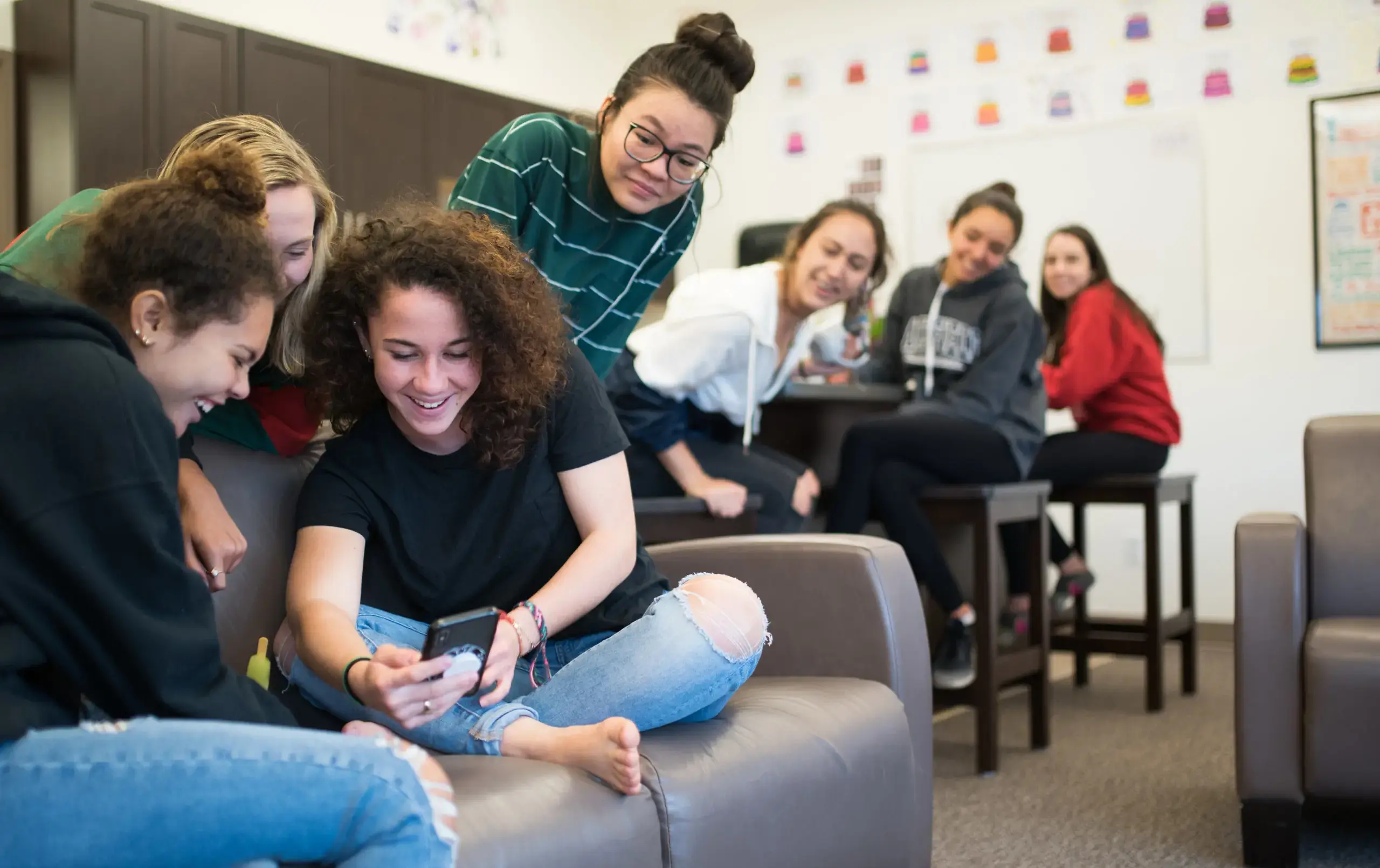 Students crowding around dormmate showing something on their phone