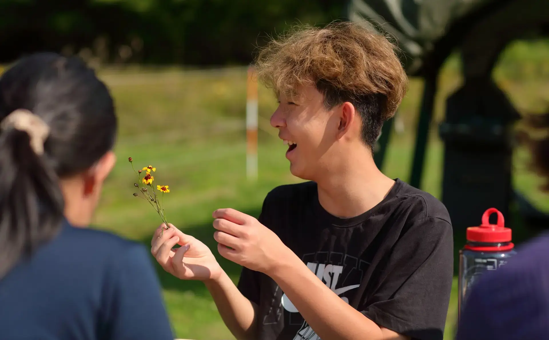 Studet smiling, holding up flower