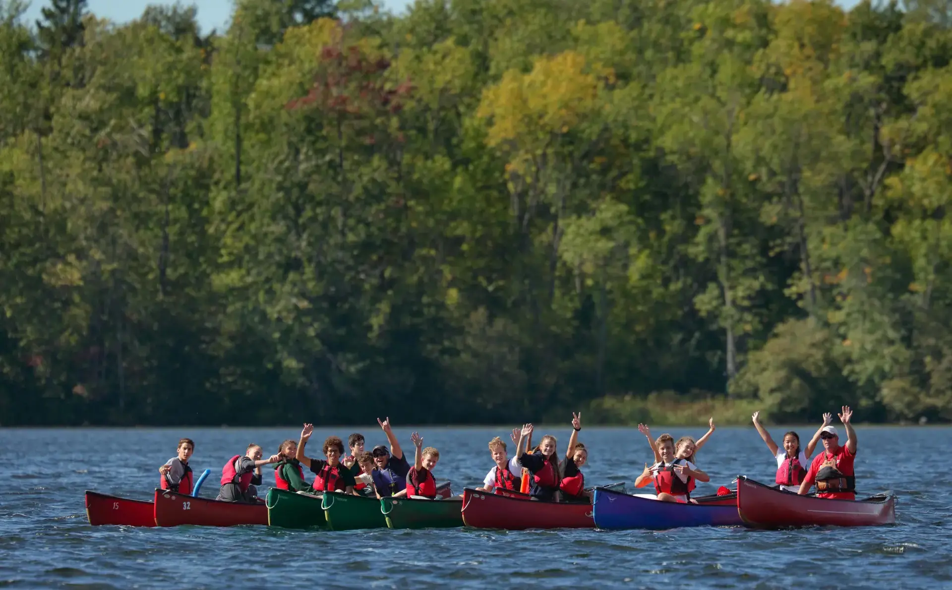 Students waving from canoes