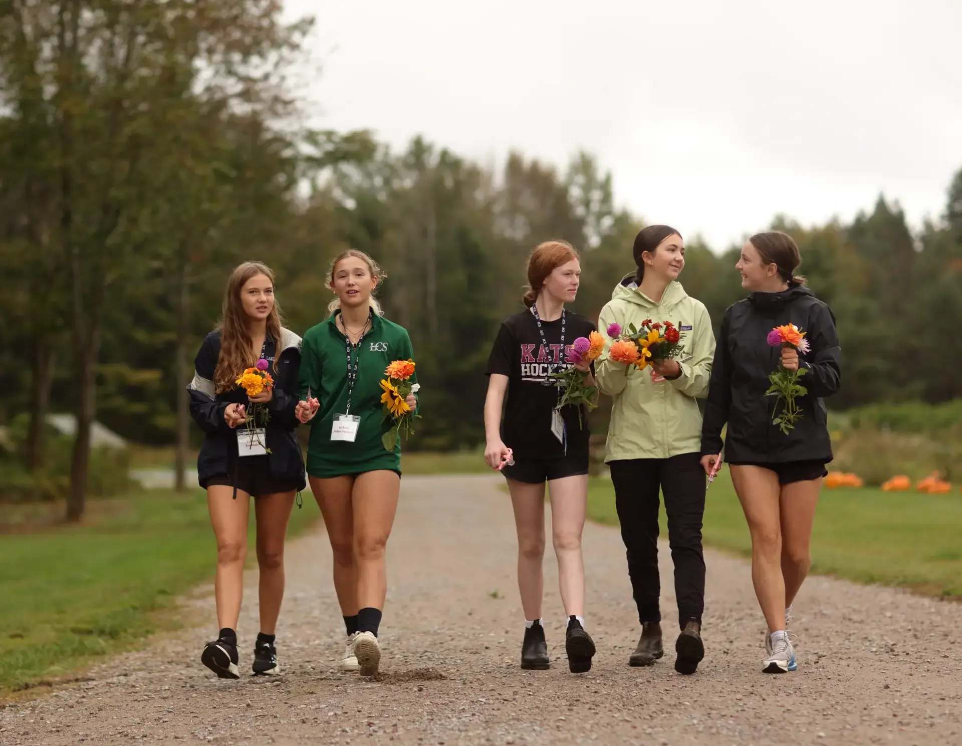 Students walking up path, holding flowers
