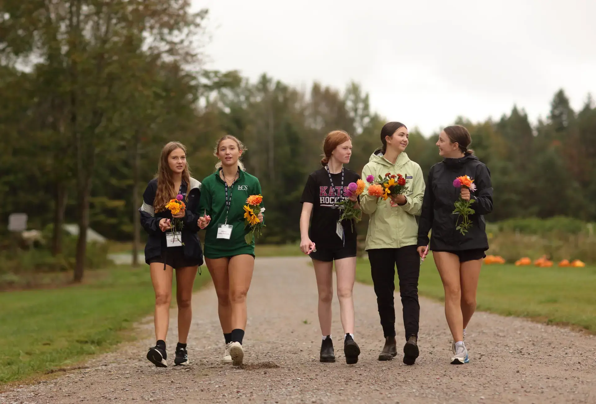 Students walking down path holding flowers