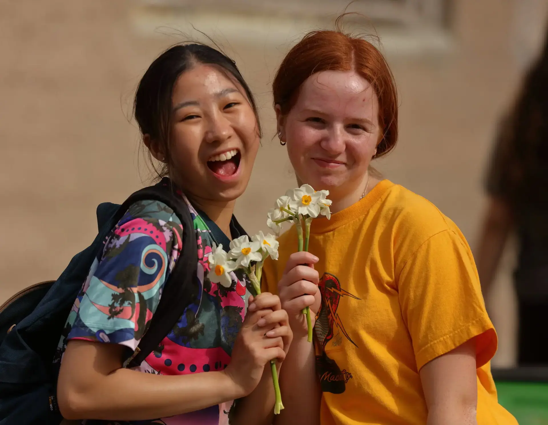 Two students smiling, holding flowers