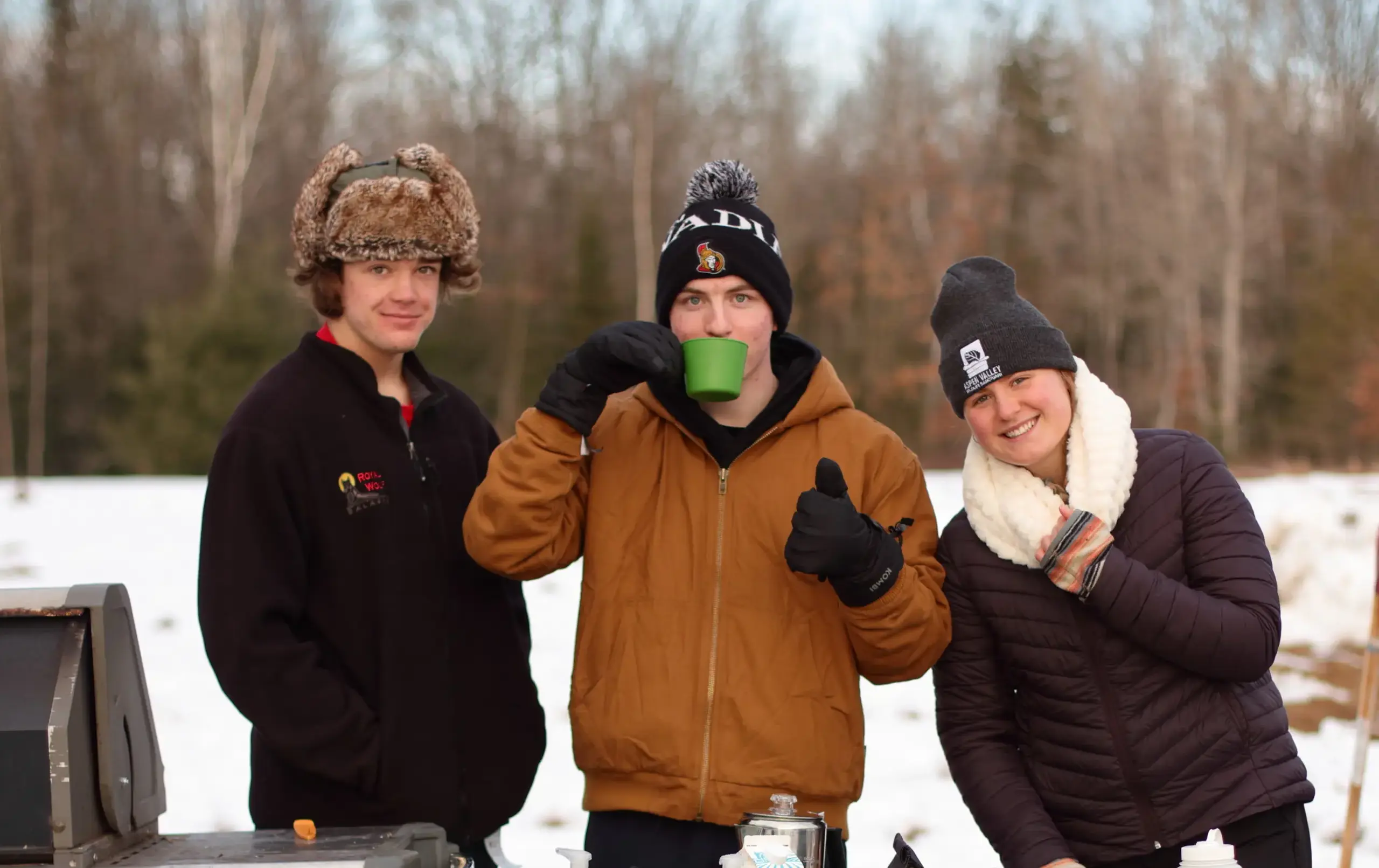Three students drinking hot drinks on winter's day
