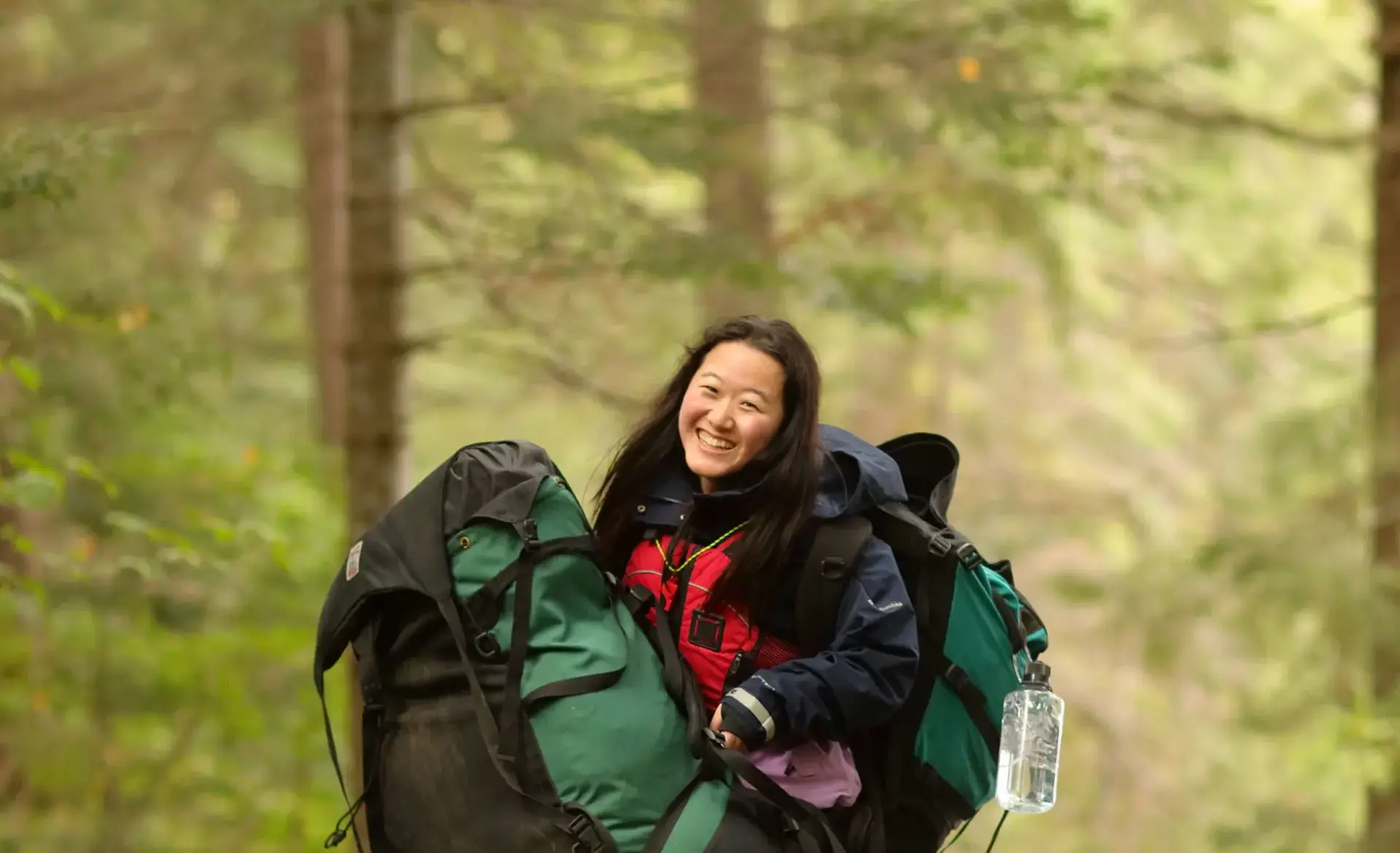 Smiling student laden with rucksacks