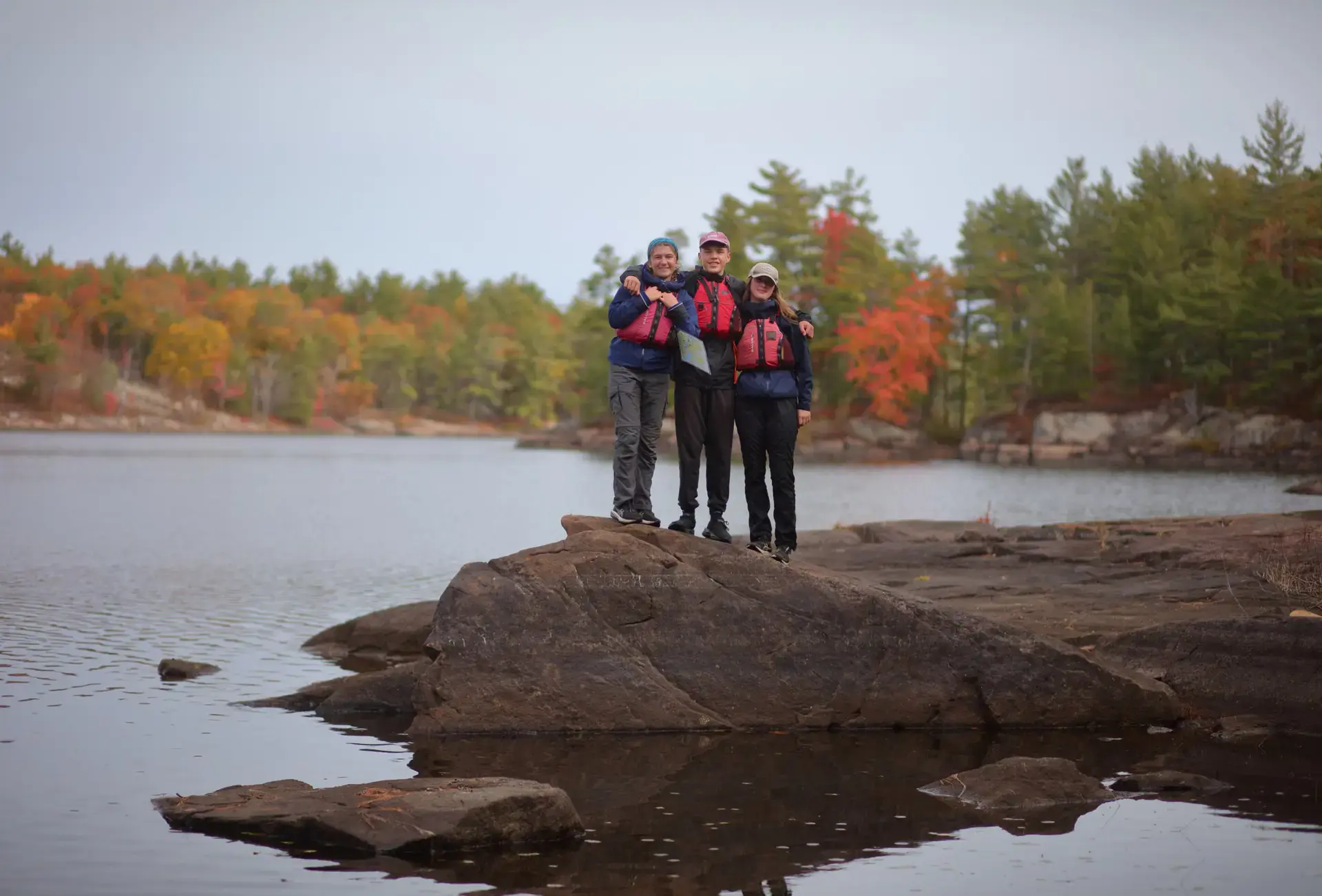 Students standing by lake on autumnal day