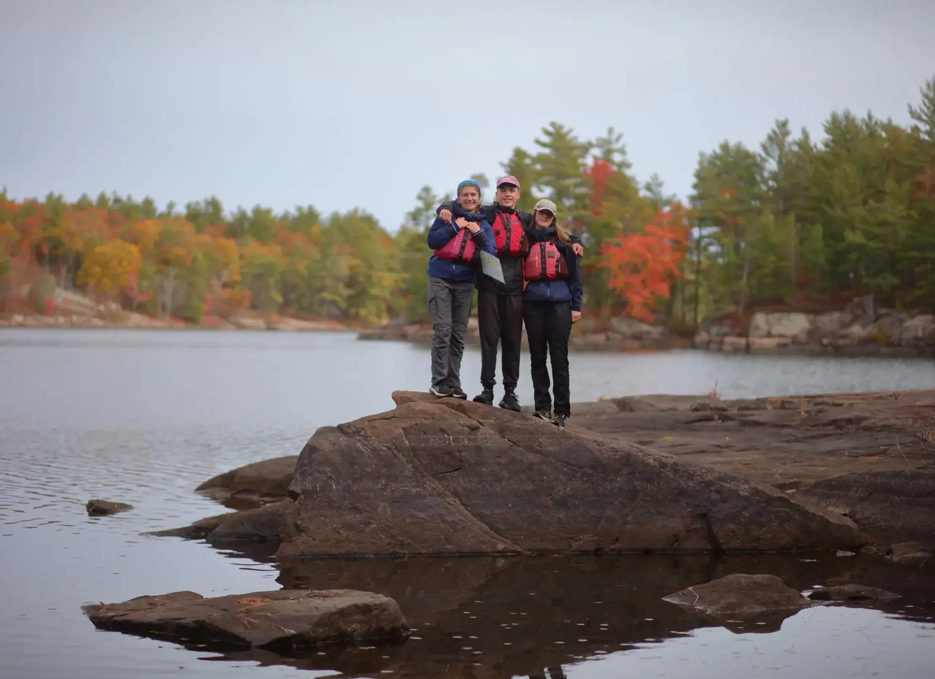 Students standing on rock on bank of lake