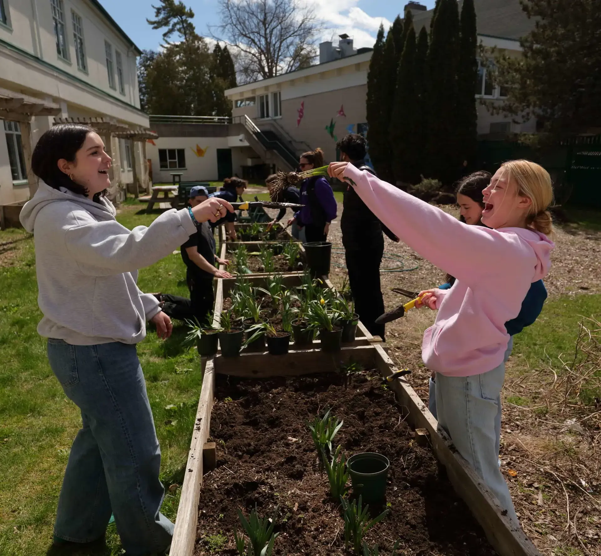 Students laughing together as they plant produce