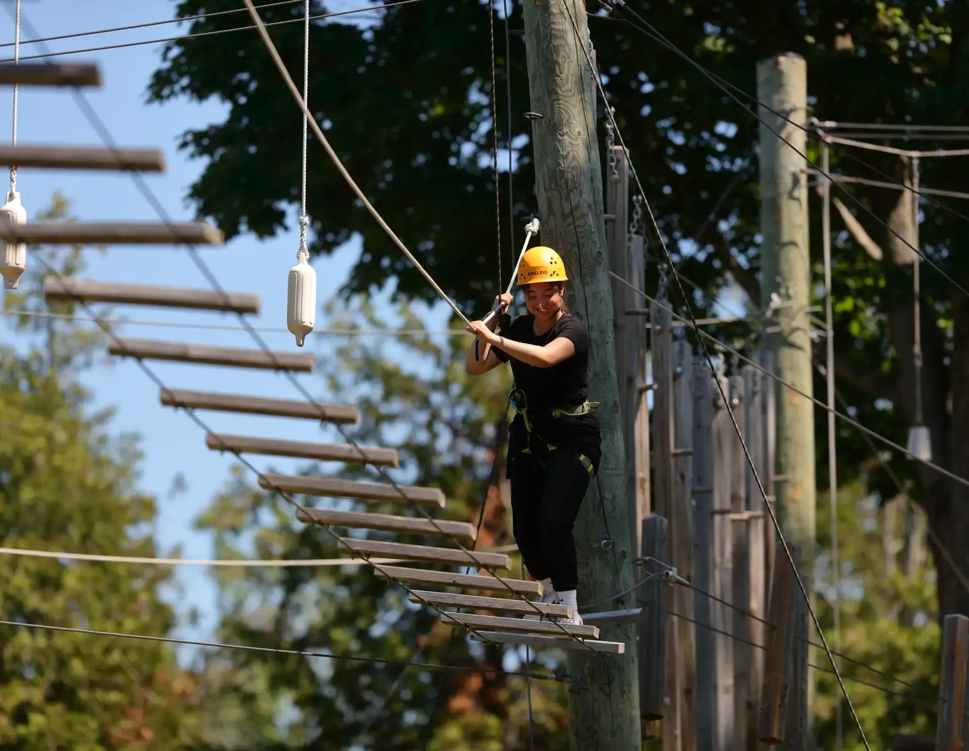 Student moving across treetop walkway