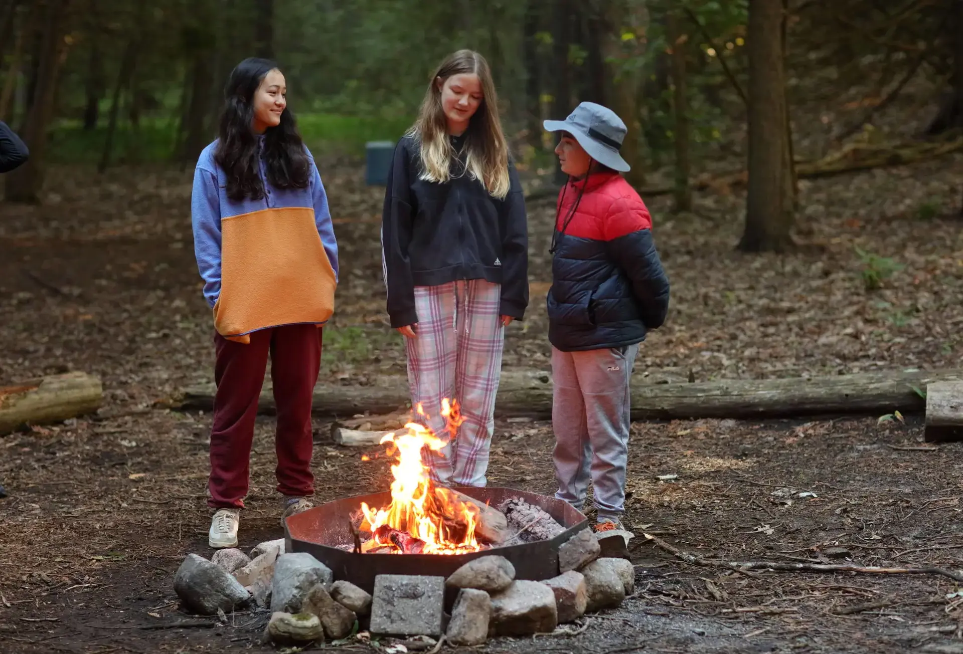 Three campers standing around fire
