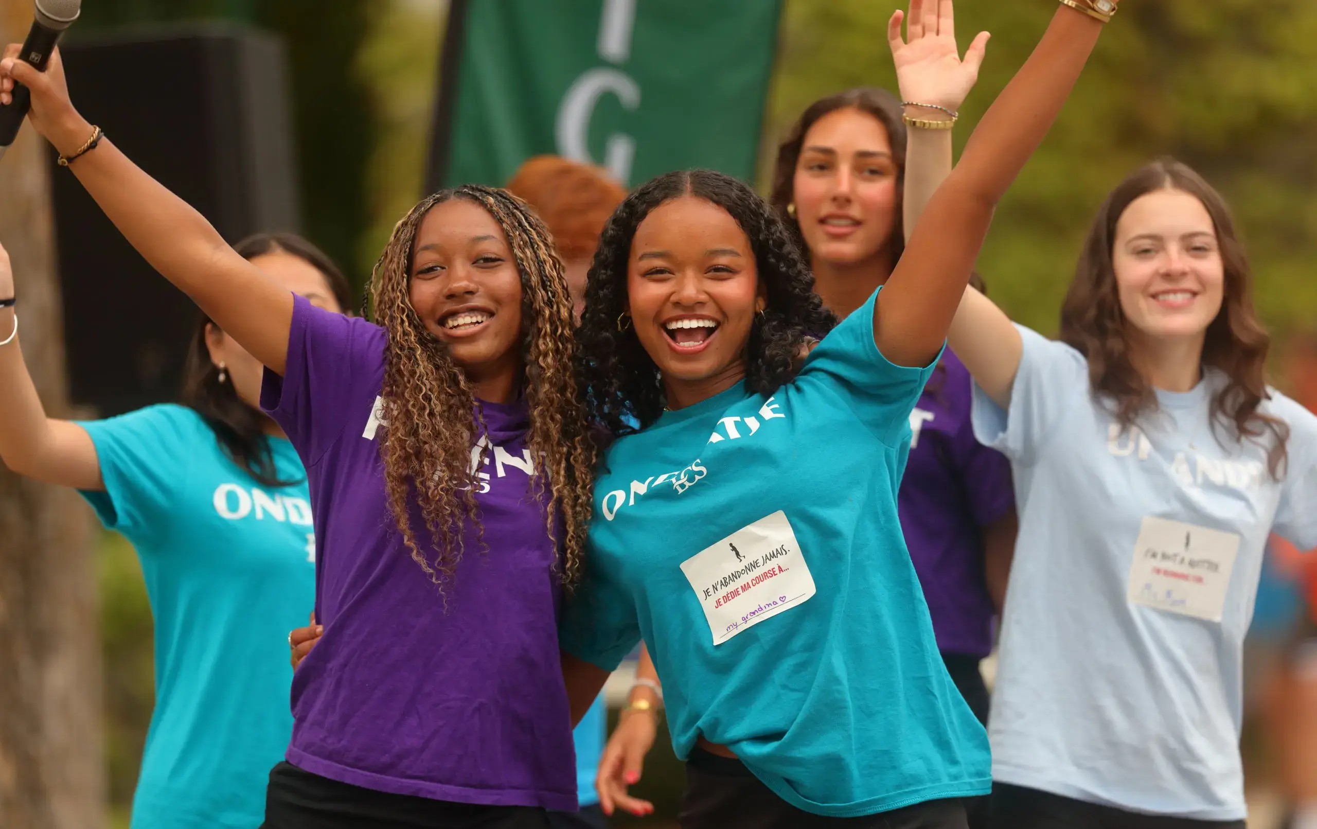 A group of students in colourful t-shirts celebrate together outdoors during a Terry Fox Run event.