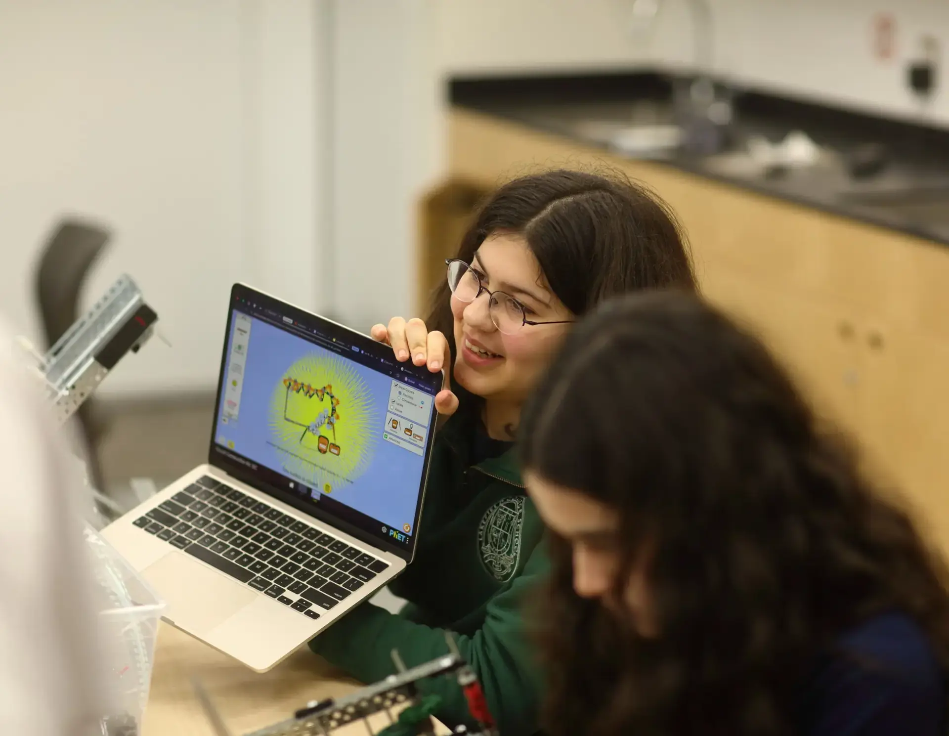 Student showing laptop to classmate