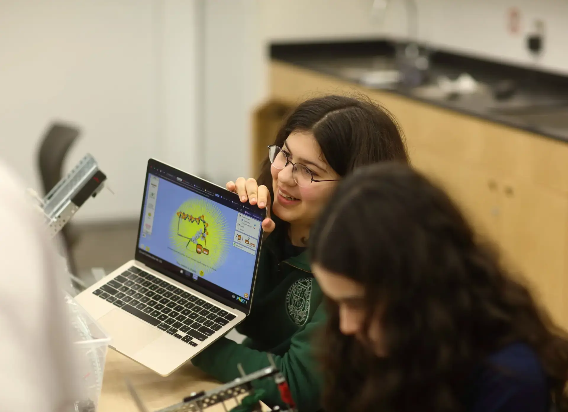 Student sharing robotics design on their laptop with other students in Robotics Club