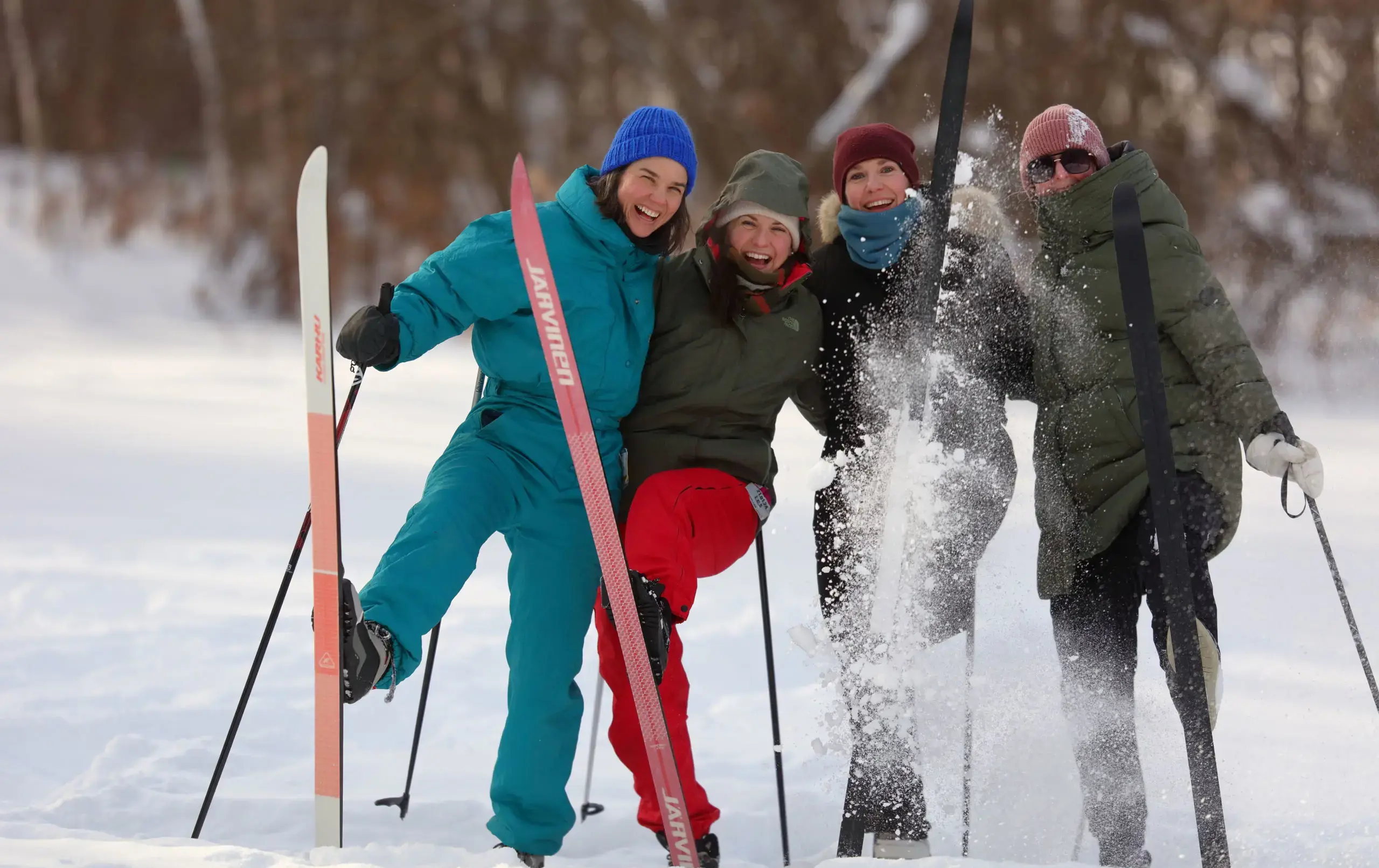 Four students holding skis, smiling