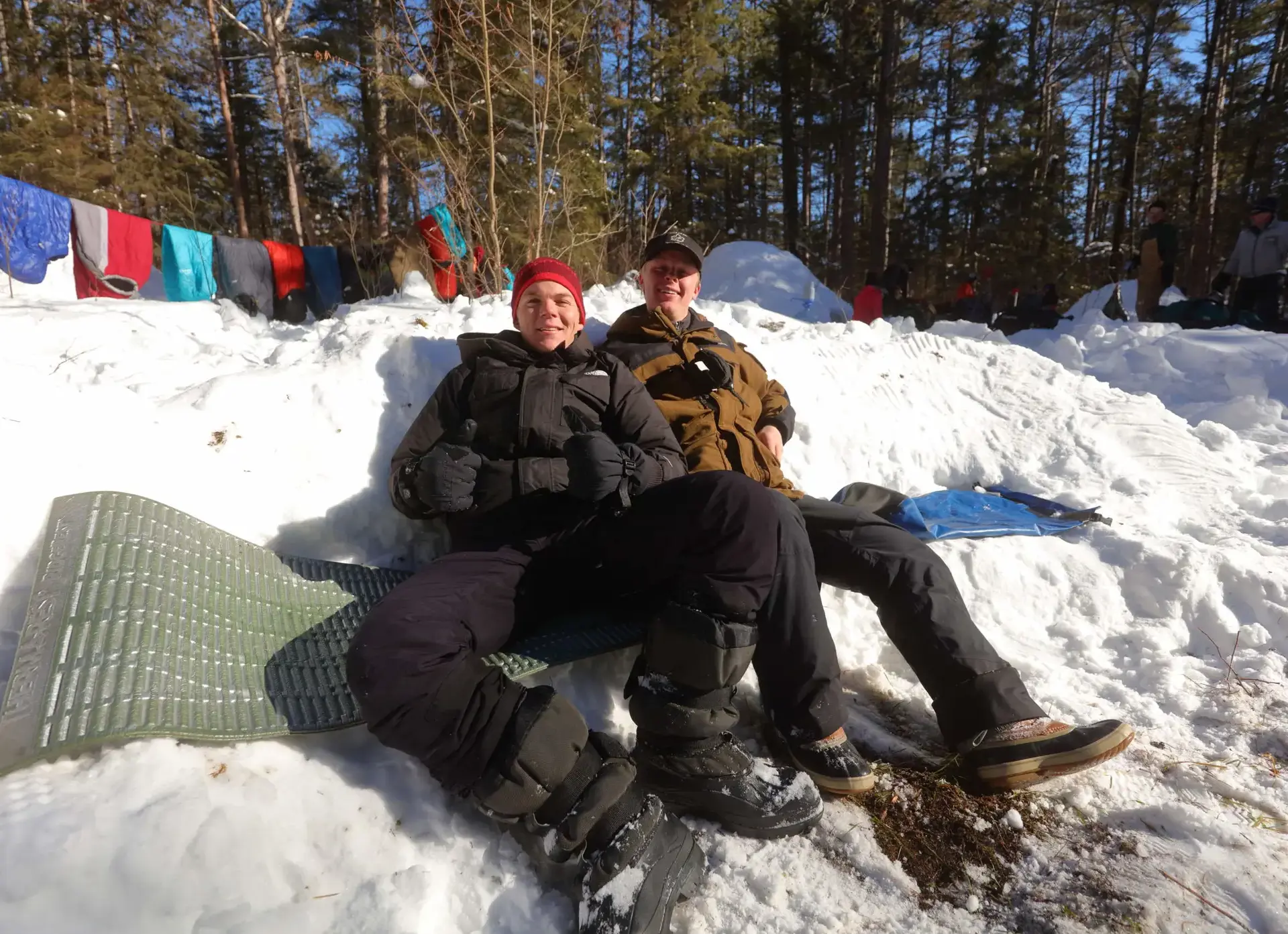 Two students lounging on snow-covered ground