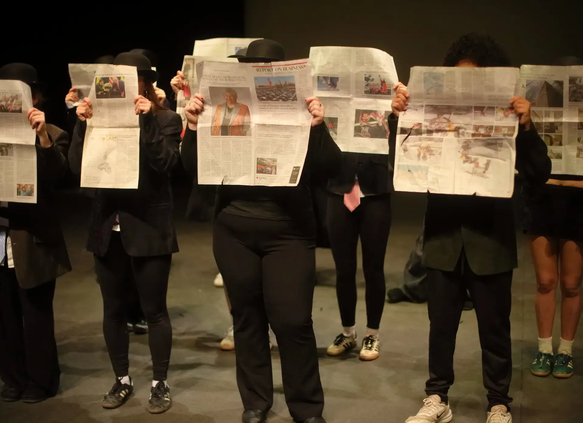 Students holding up newspapers in play