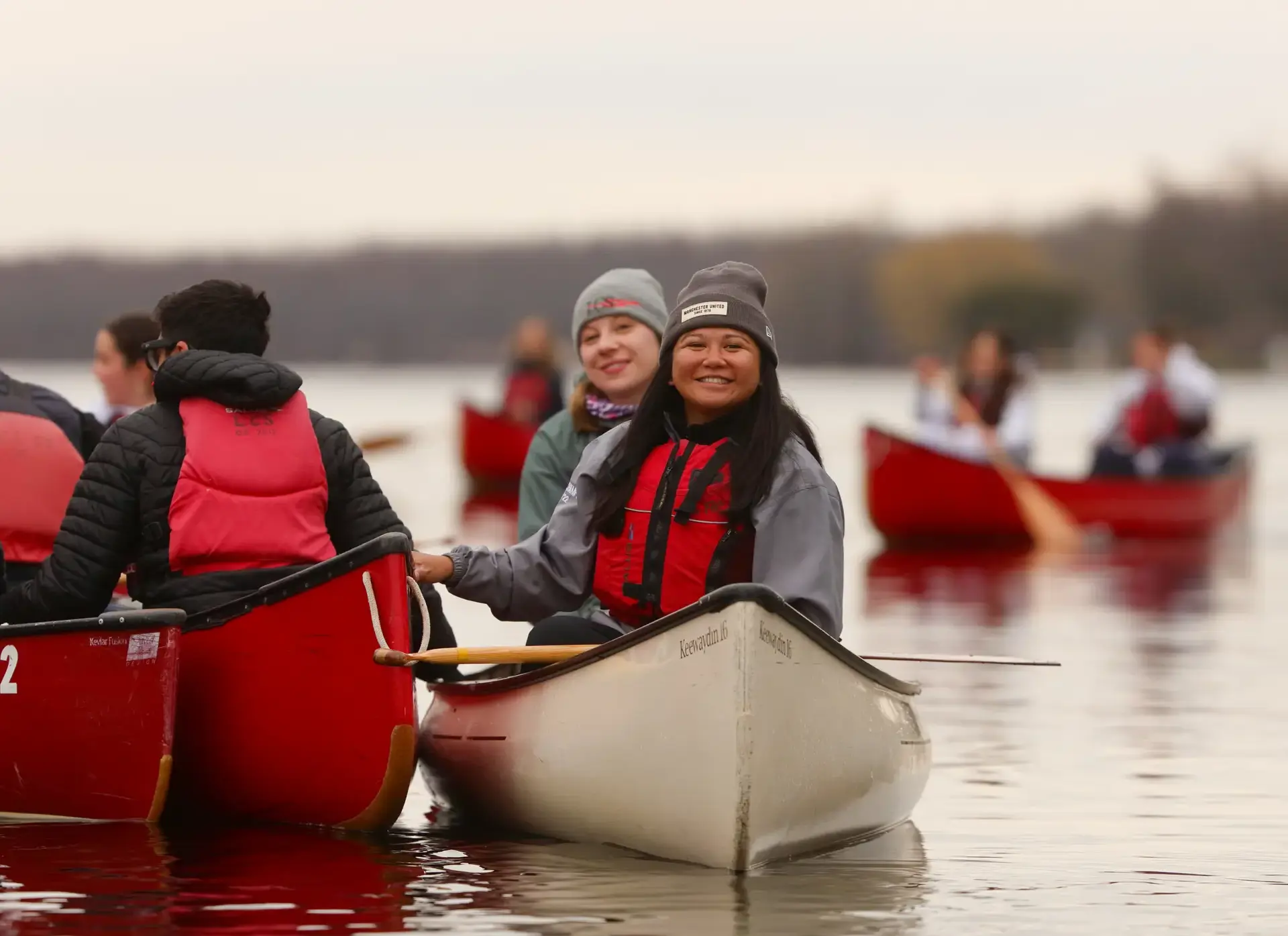Staff smiling in a canoe out for sunrise paddle with other staff and students