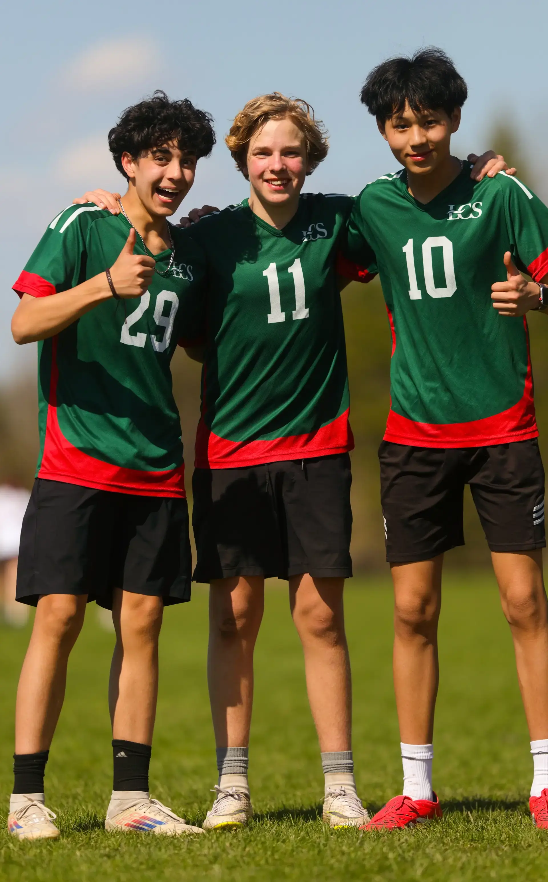 Students in soccer outfits with smiles and thumbs ups