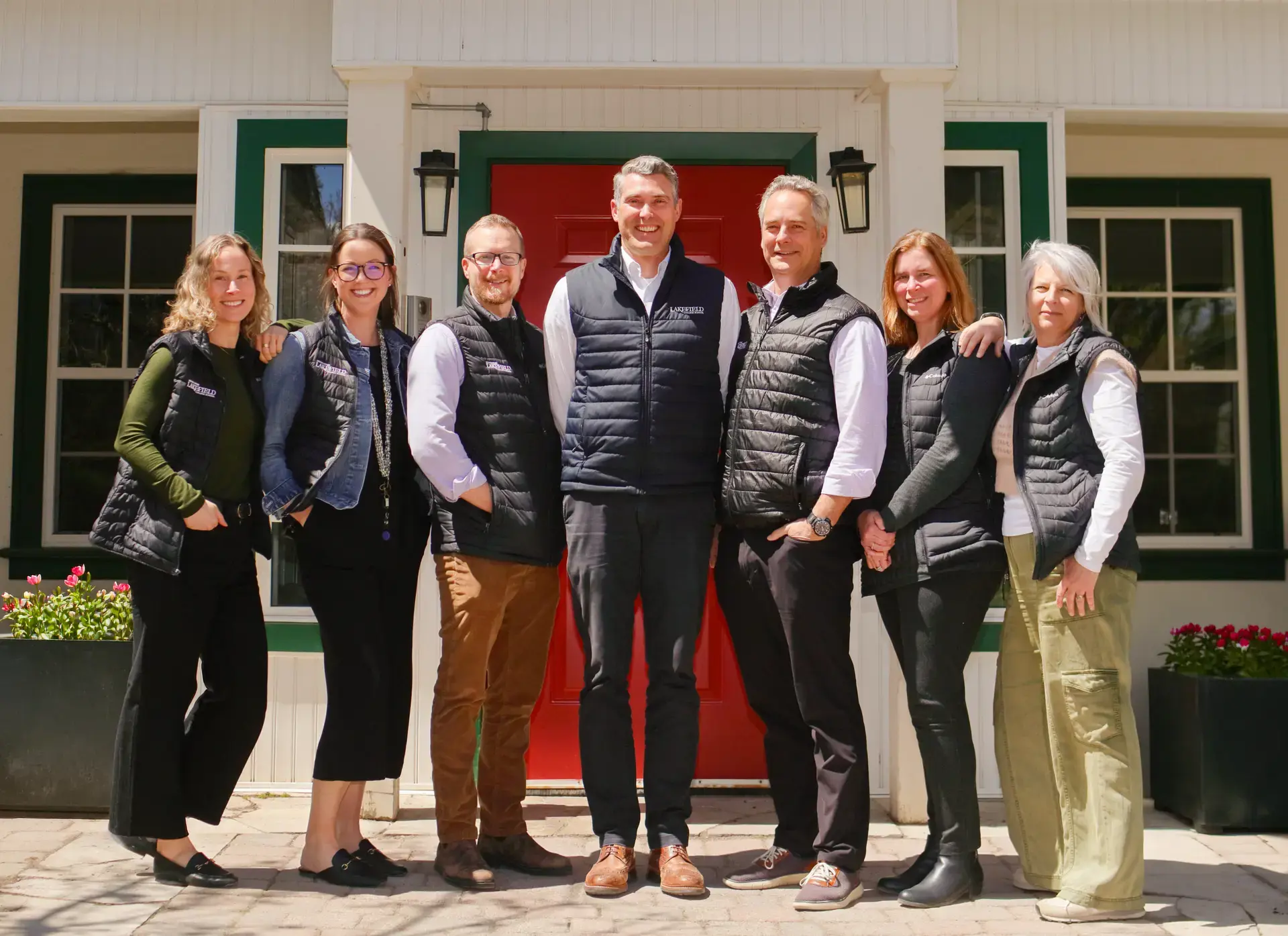 Admissions team standing outside the red door to Grove House and Reception