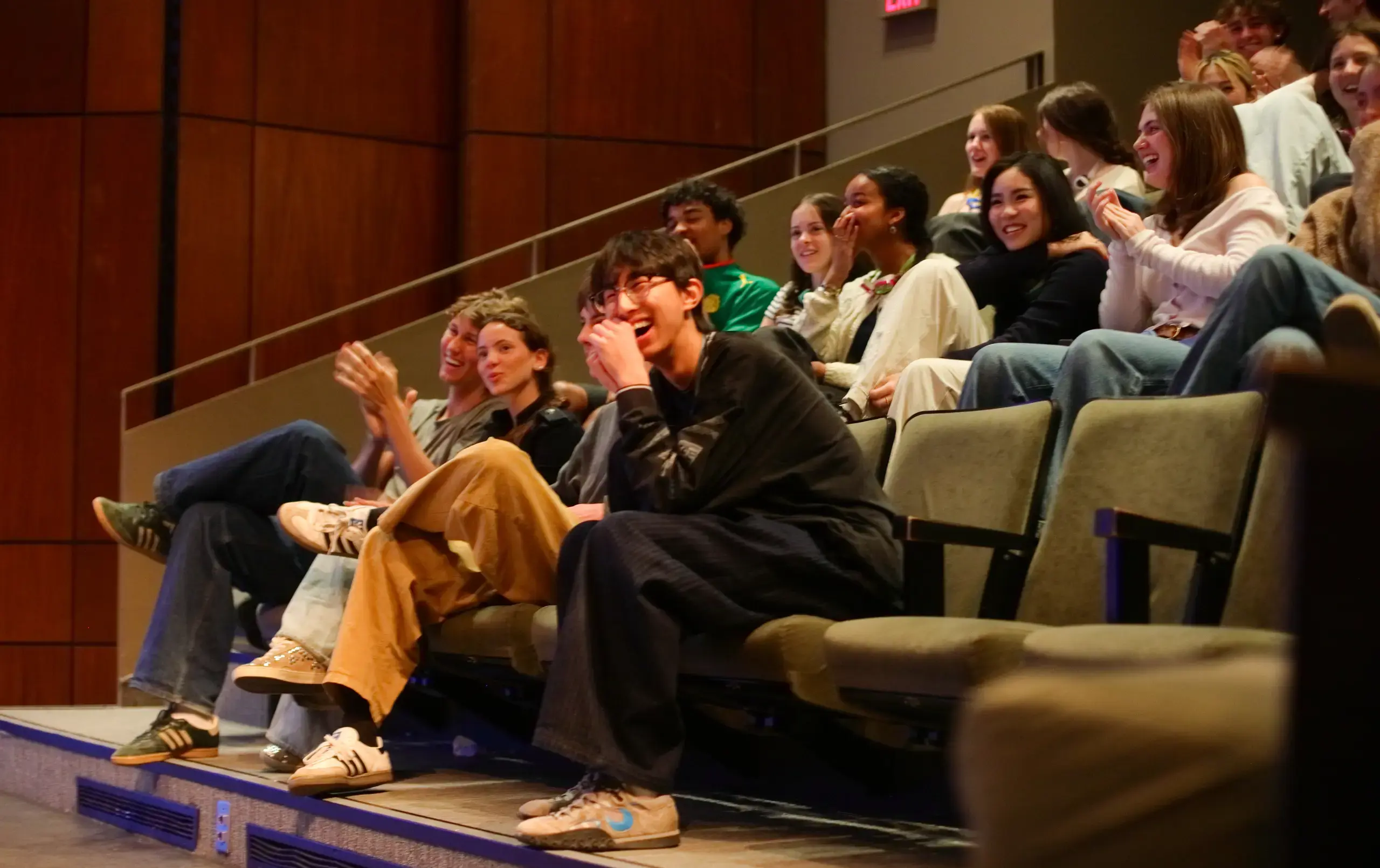 Group of students during intersession watching a performance in the theatre with joy and laughter