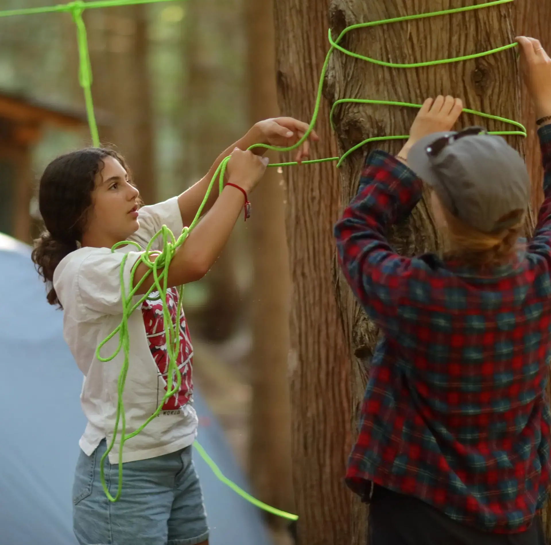 Campers tying rope around tree