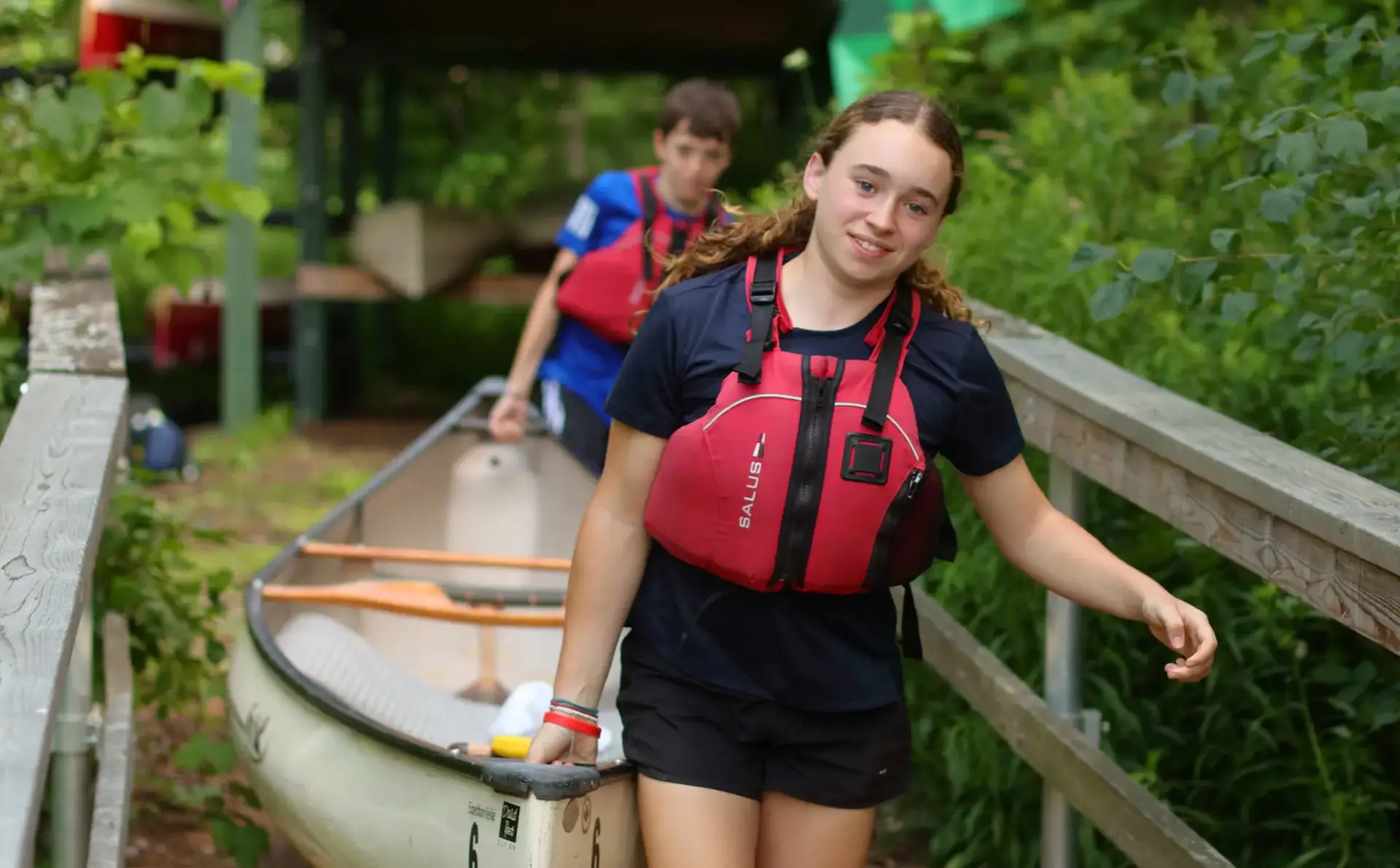 Students carrying canoe down jetty