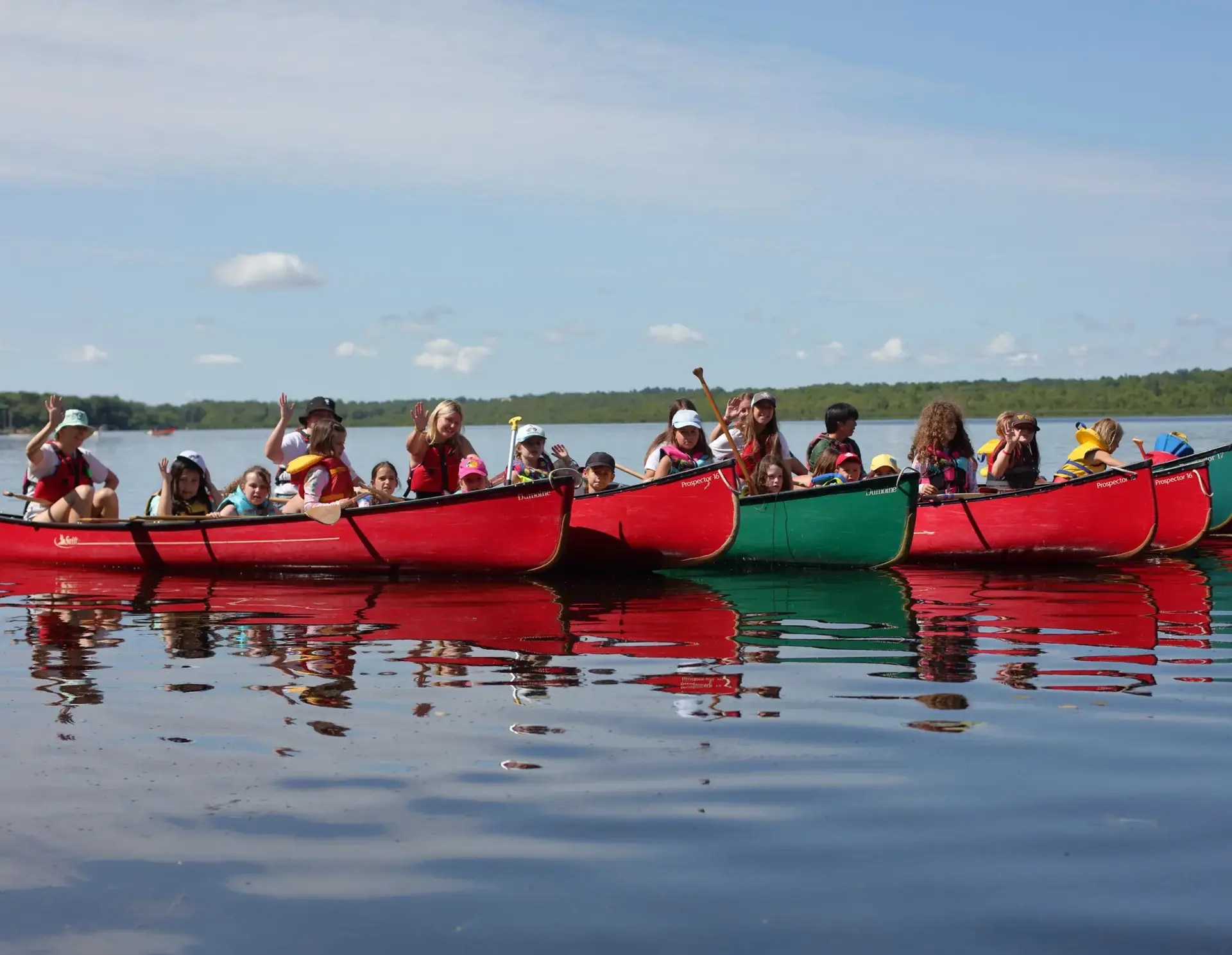 Students sitting in line of canoes
