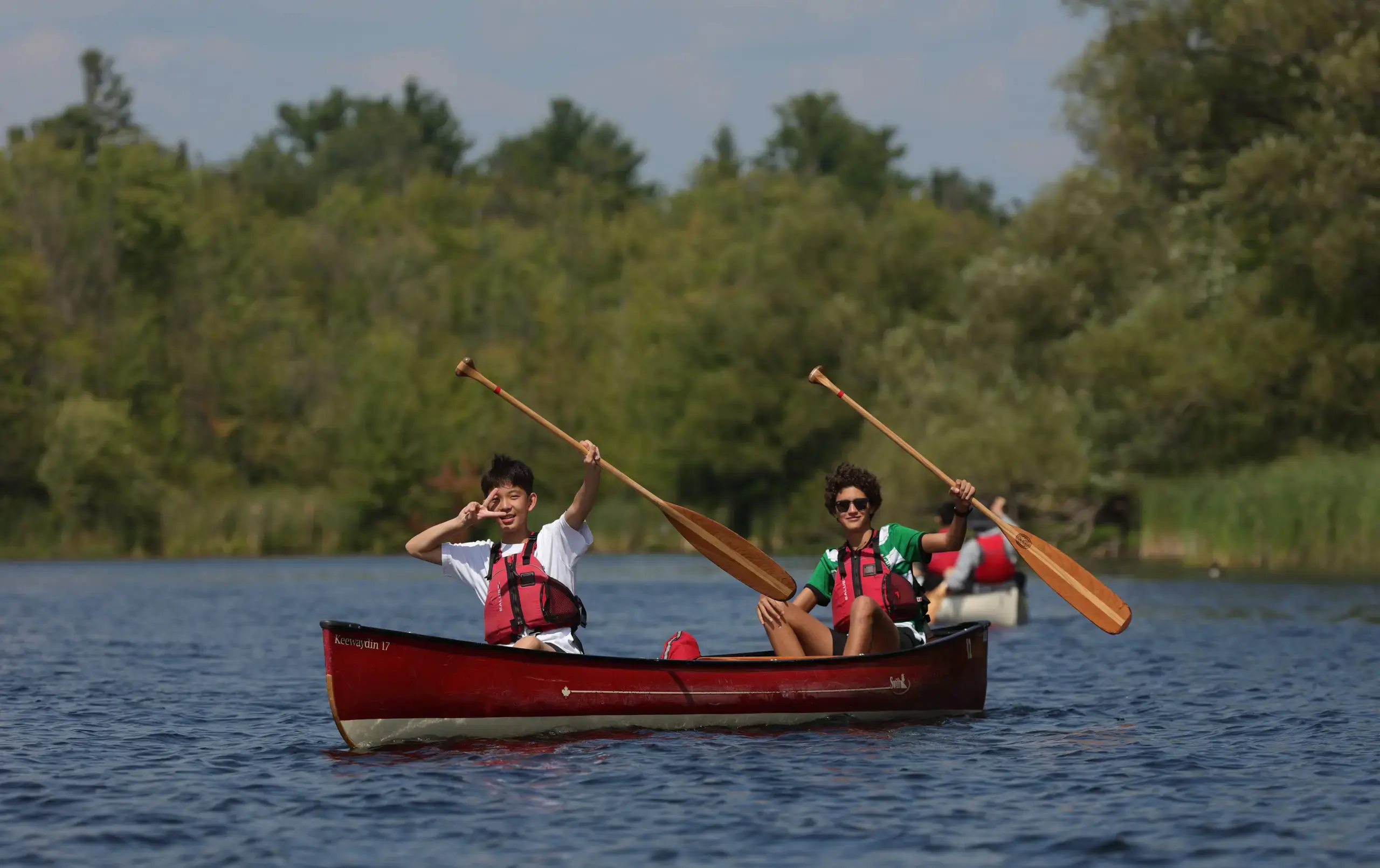 Students waving from canoes