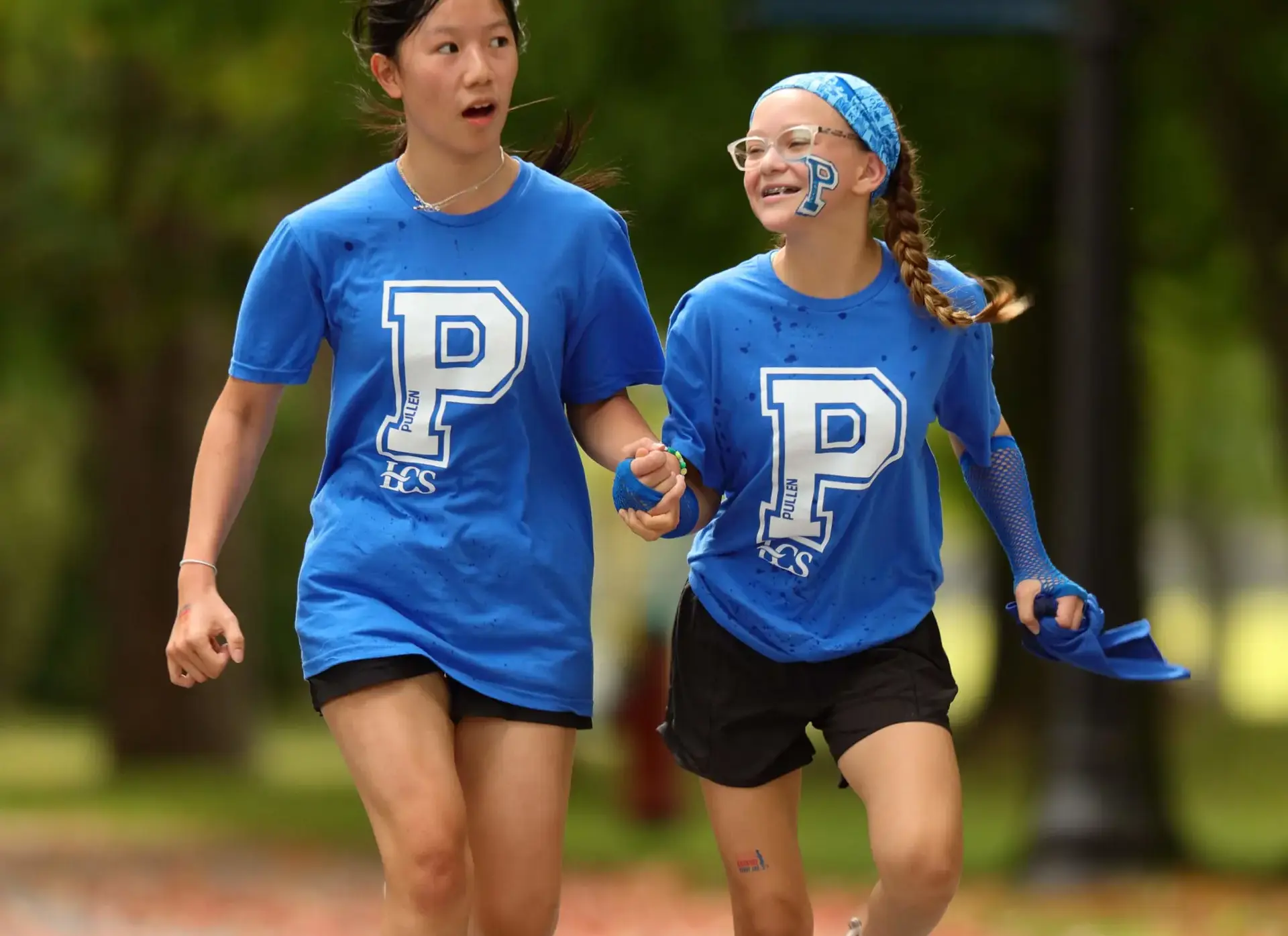 Two students wearing blue jerseys, participating in distance run
